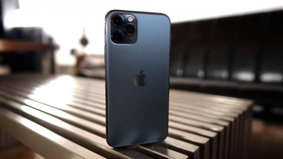 iPhone 11 桌布 壁紙 — 一部纖薄的藍色 iPhone 12 Pro Max 直立於金屬條紋長凳上，背景柔和模糊。