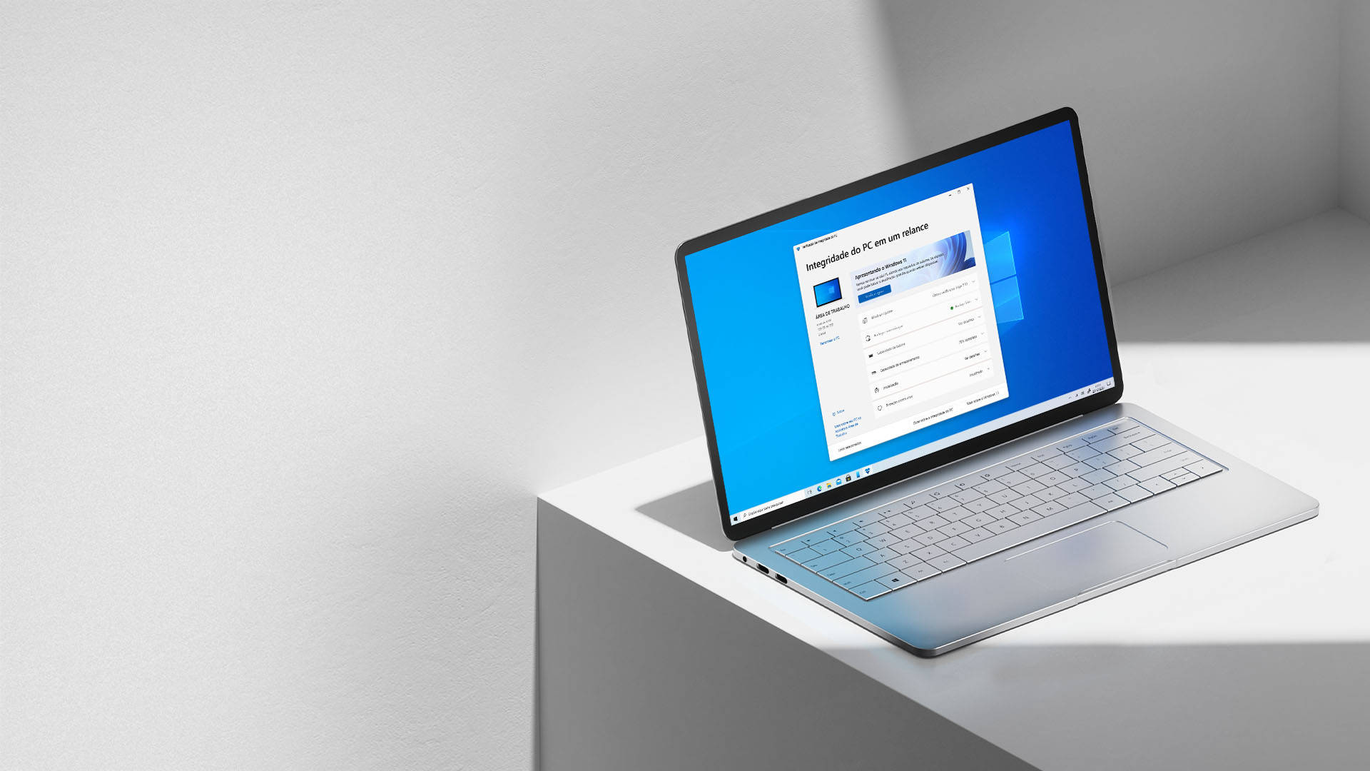 Windows 11 桌布 壁紙 — 一部纖薄的銀色筆記型電腦在簡約的白色邊緣上打開，在明亮的攝影棚燈光下顯示 Windows 設定畫面。