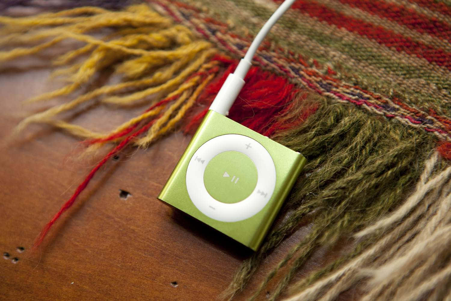 Music Player 桌布 壁紙 — 一部萊姆綠色的 iPod classic 放在木質表面上色彩繽紛的流蘇紡織品上。