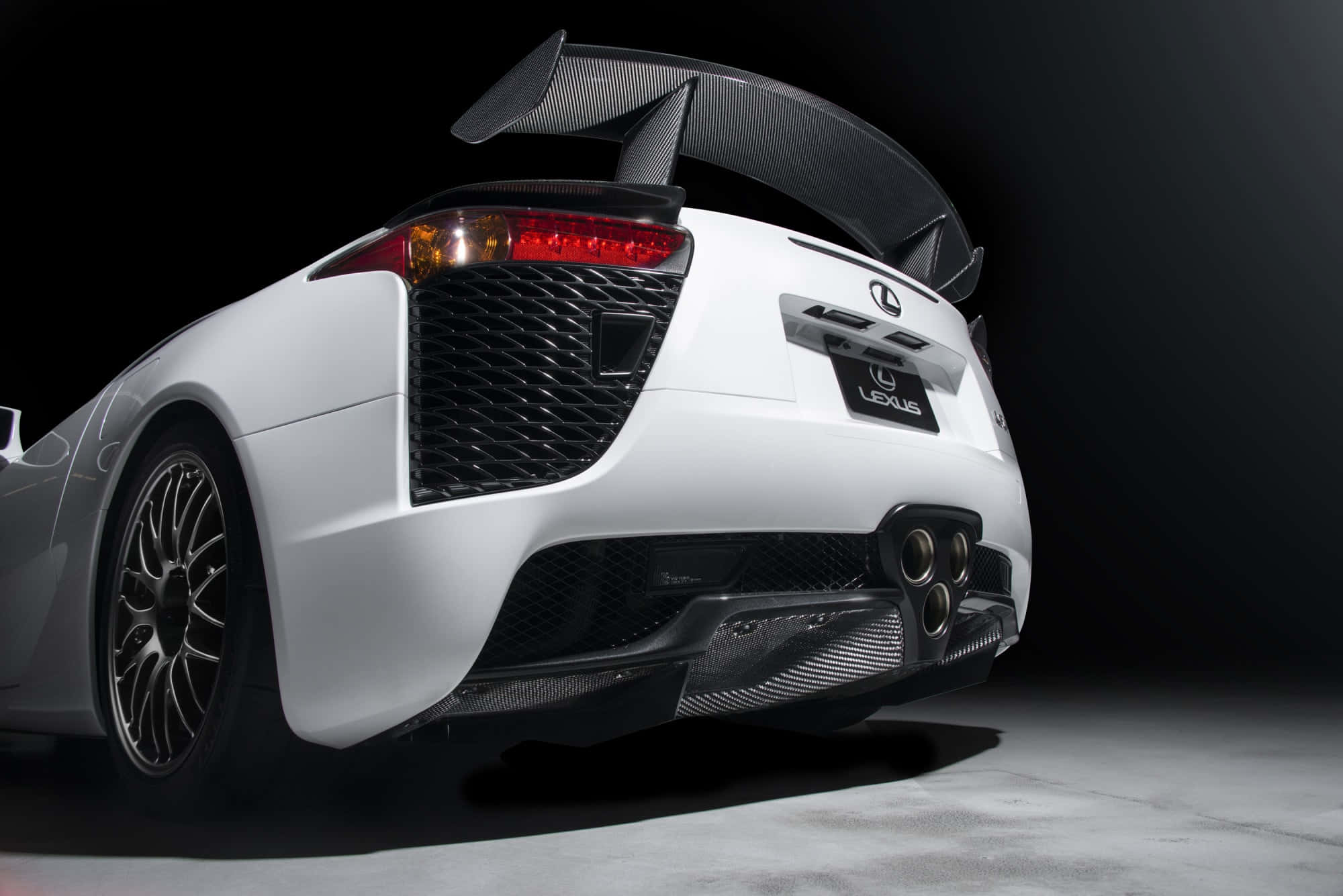 Lexus Lfa 桌布 壁紙 — 一部配備碳纖維尾翼和四出排氣管的白色Lexus LFA跑車，在黑暗背景下的戲劇性工作室聚光燈中展示。