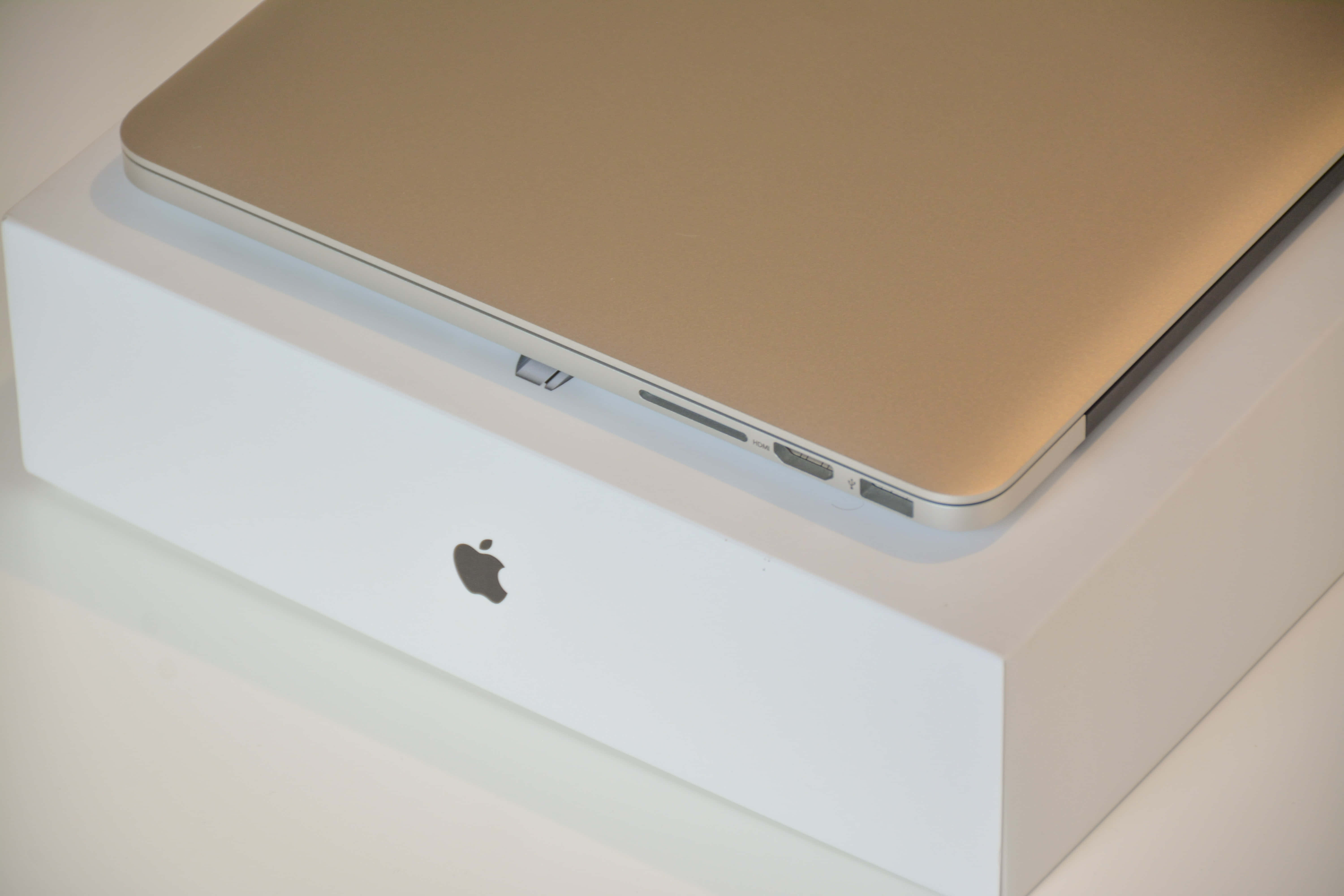 美學 MacBook 壁紙 桌布 壁紙 — 一部金色 MacBook 優雅地放在白色 Apple 盒上，邊緣可見連接埠。