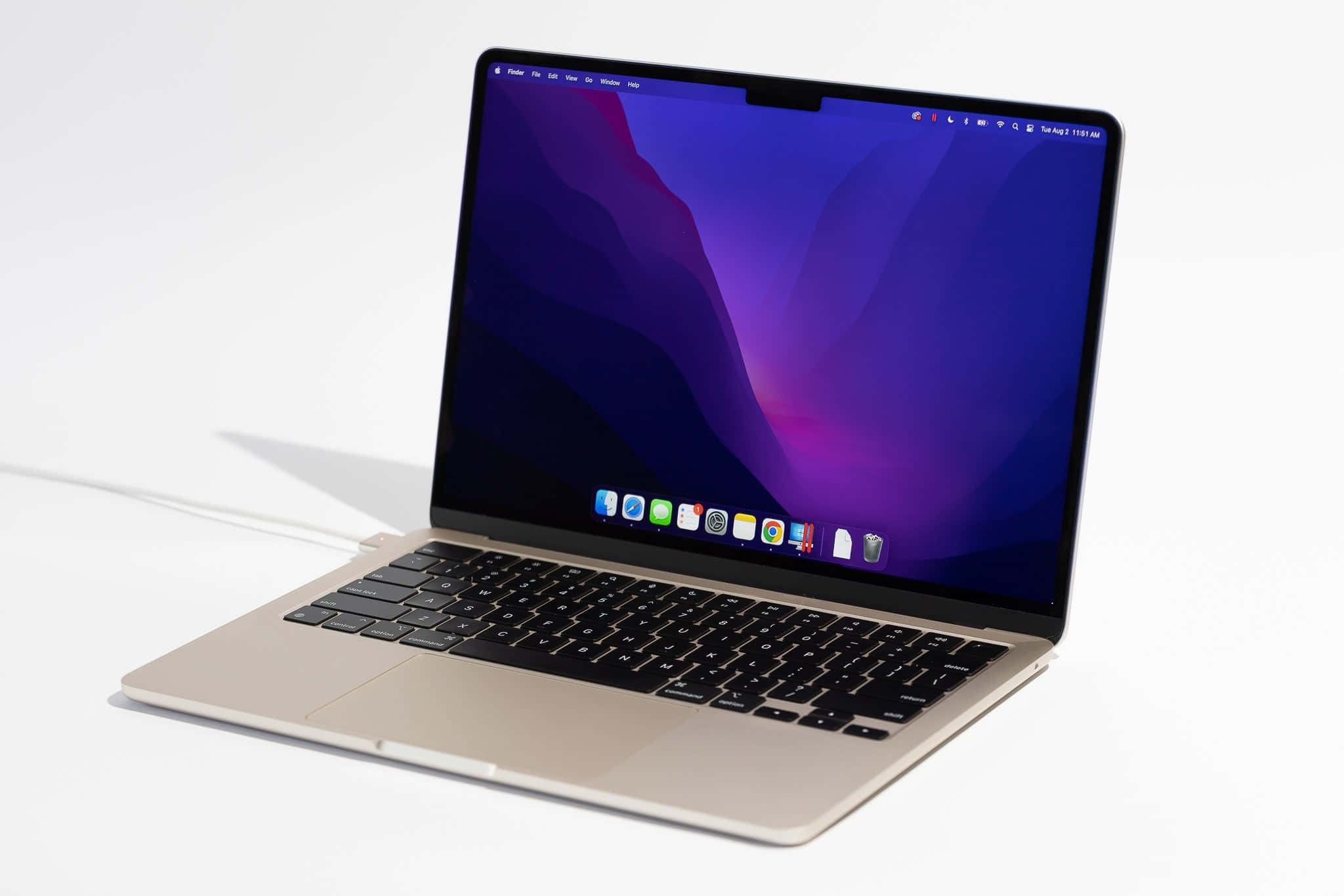 Mac 桌布 壁紙 — 一部金色筆記型電腦帶有紫色漸層桌布，打開放在白色表面上，投下柔和陰影。