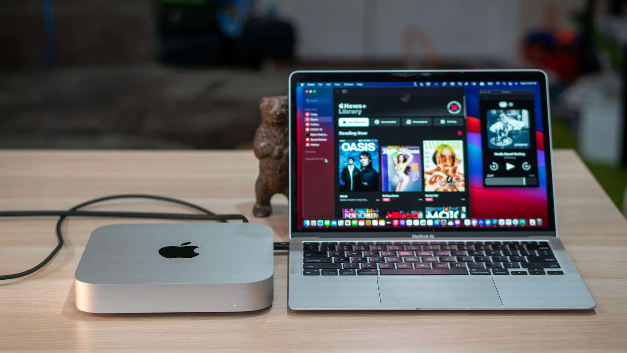 MacBook 動態圖片 桌布 壁紙 — 一部銀色 Mac mini 和 MacBook Pro 並排放在木桌上，附近有一個小熊公仔。