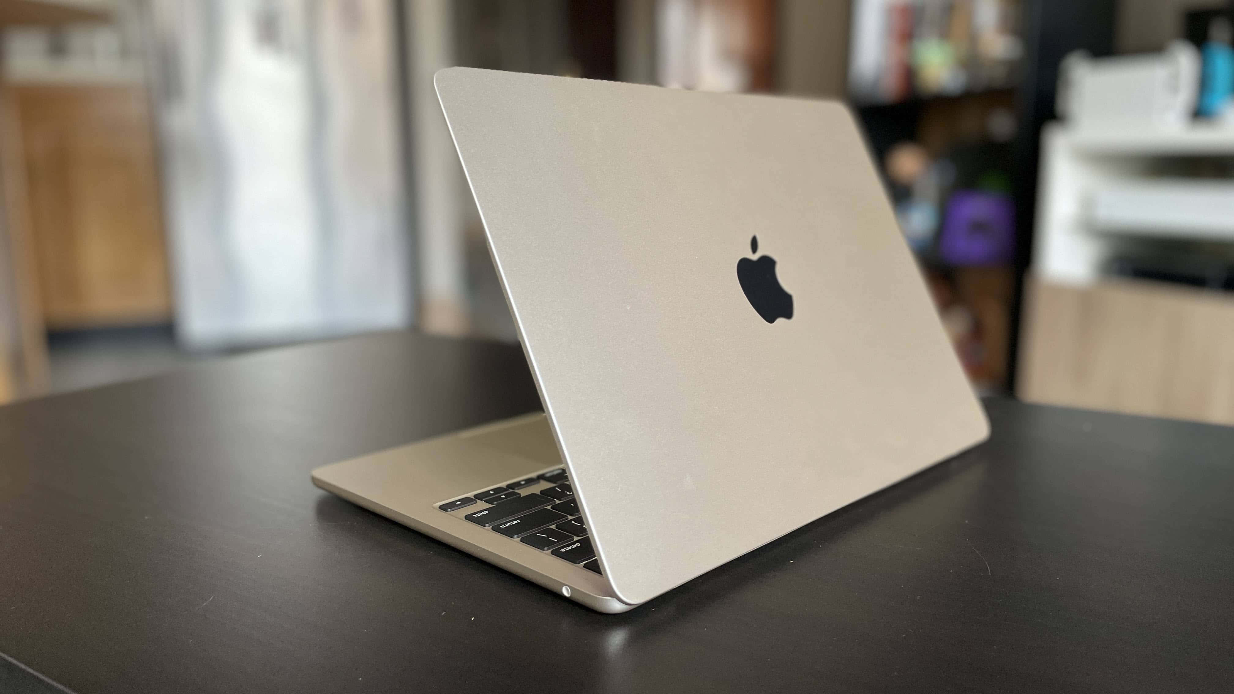 MacBook 動態圖片 桌布 壁紙 — 一部銀色 MacBook 筆記型電腦打開放在深色木桌上，處於柔和光線的室內環境。