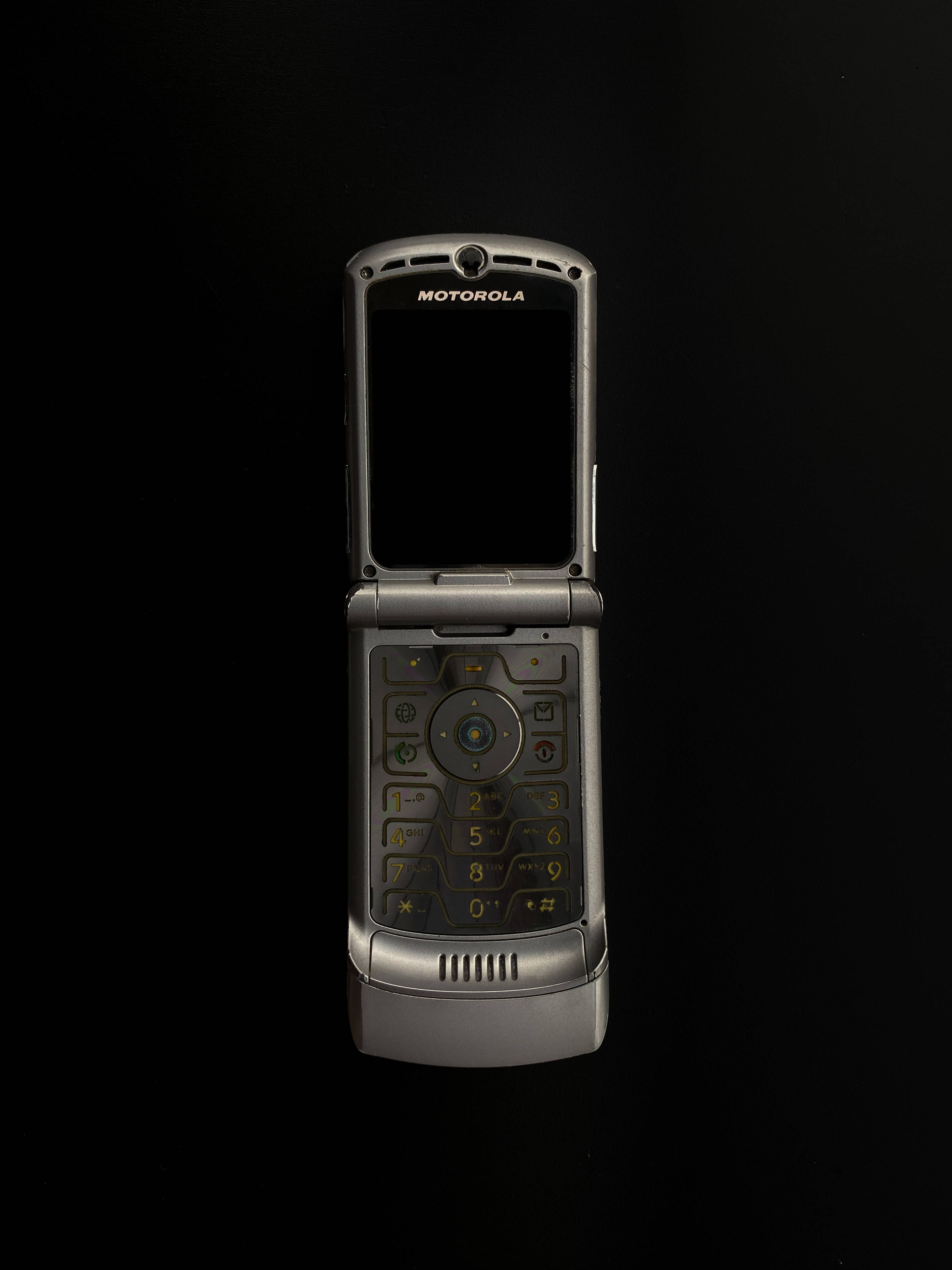 摩托羅拉 桌布 壁紙 — 一部銀色 Motorola 摺疊手機打開，在純黑背景上突顯其鍵盤和螢幕。