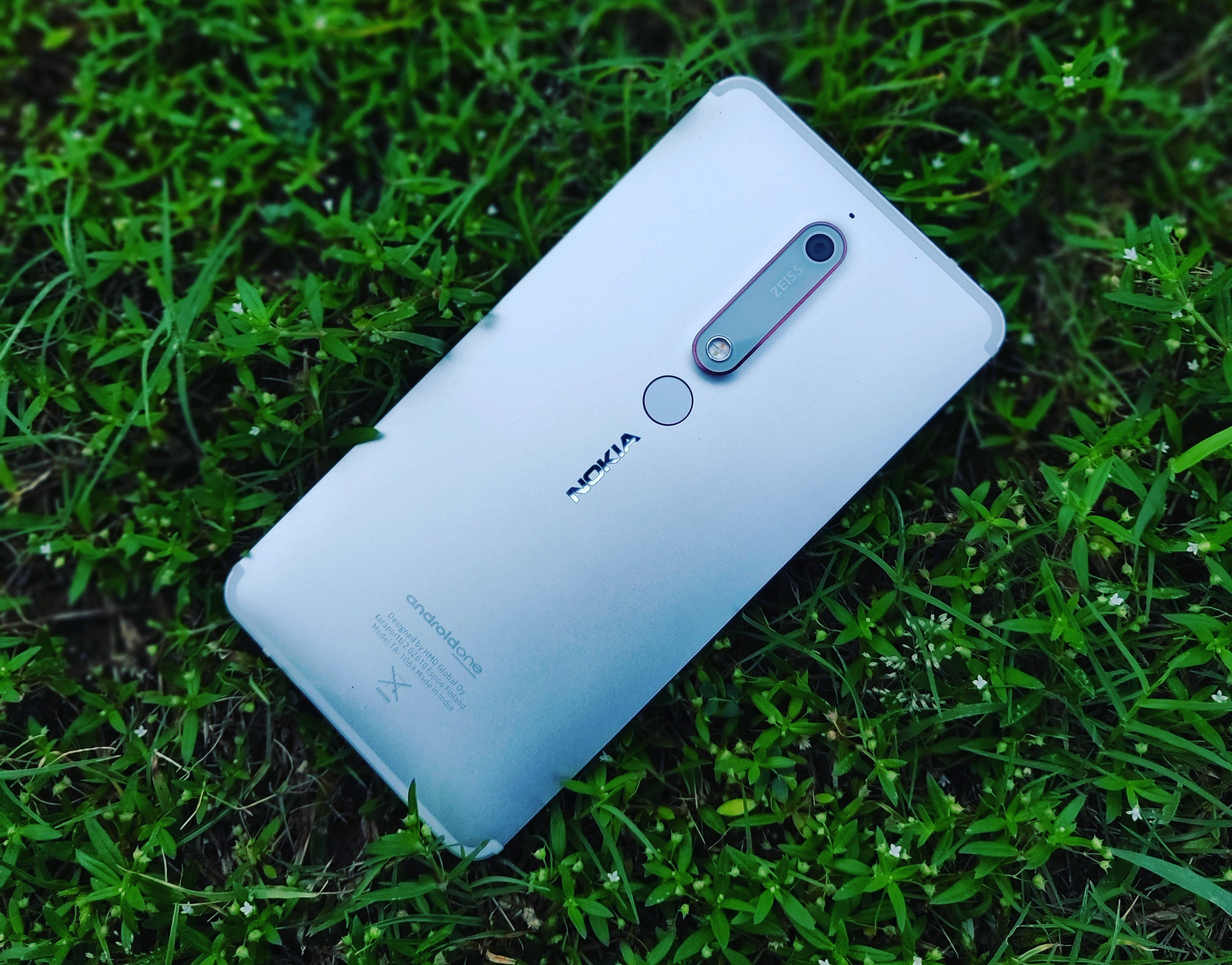 諾基亞 桌布 壁紙 — 一部銀色 Nokia 智慧型手機對角放置在點綴著細小白花的鮮綠色草地上。