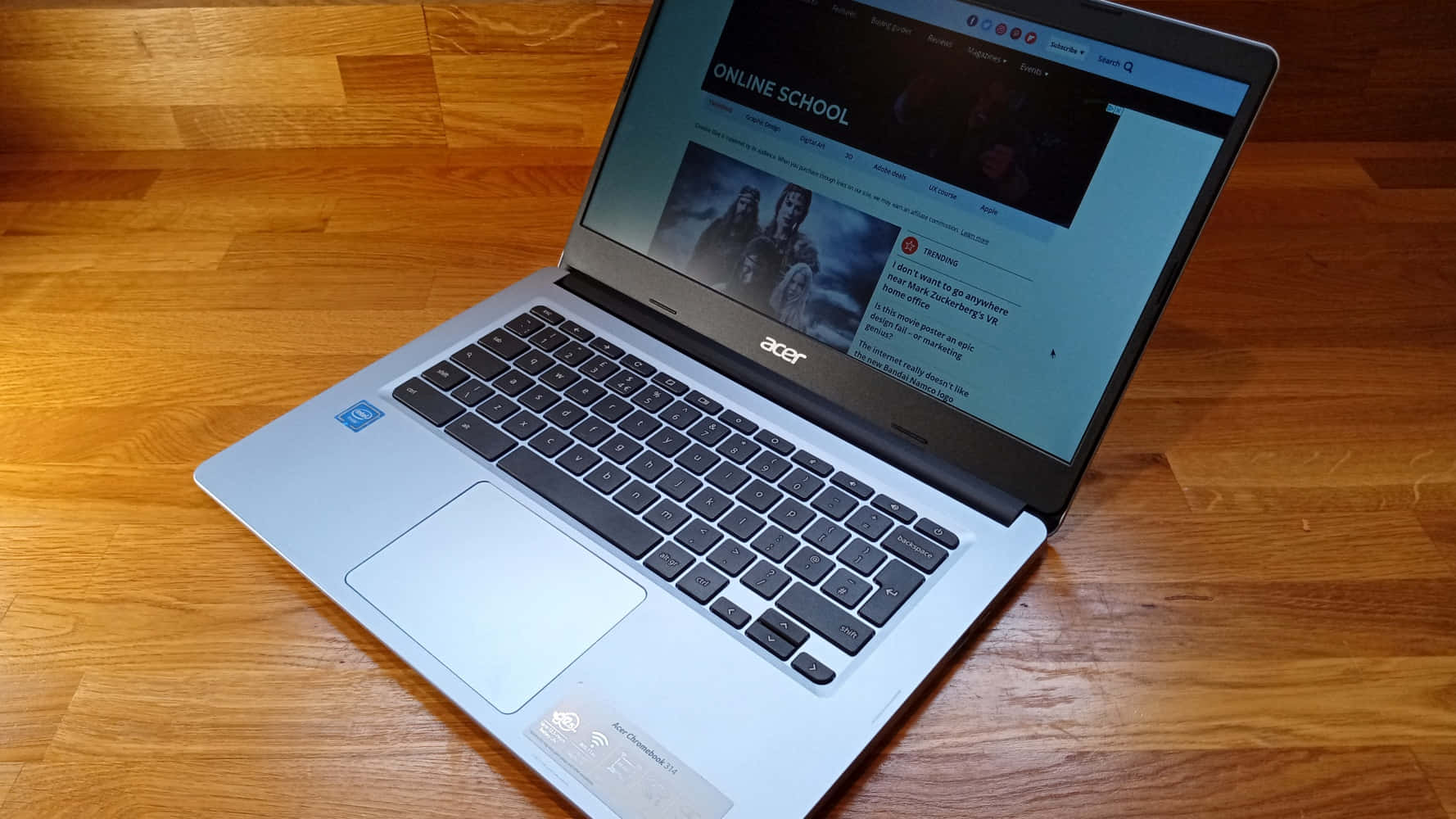 Chromebook 桌布 壁紙 — 一部銀色Acer筆記型電腦打開放在木地板上，顯示一個帶有深色英雄圖片的線上學校網頁。