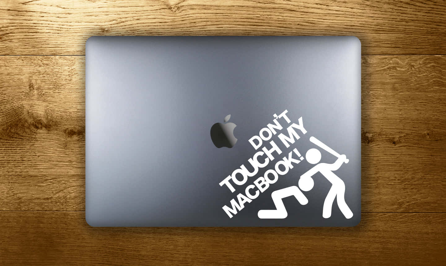 桌布 壁紙 — 一部銀色MacBook，上面貼有白色「Don't Touch My Macbook!」貼紙，放在溫暖的木質表面上。