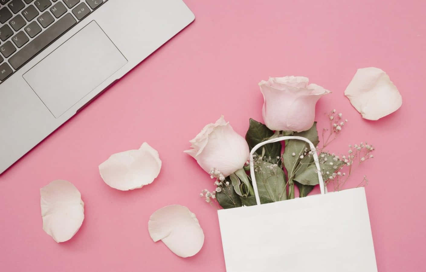 Pink Laptop 桌布 壁紙 — 一部銀色筆記型電腦放在一個裝有粉紅玫瑰和滿天星的白色手提袋旁邊，置於柔軟的粉紅色表面上。