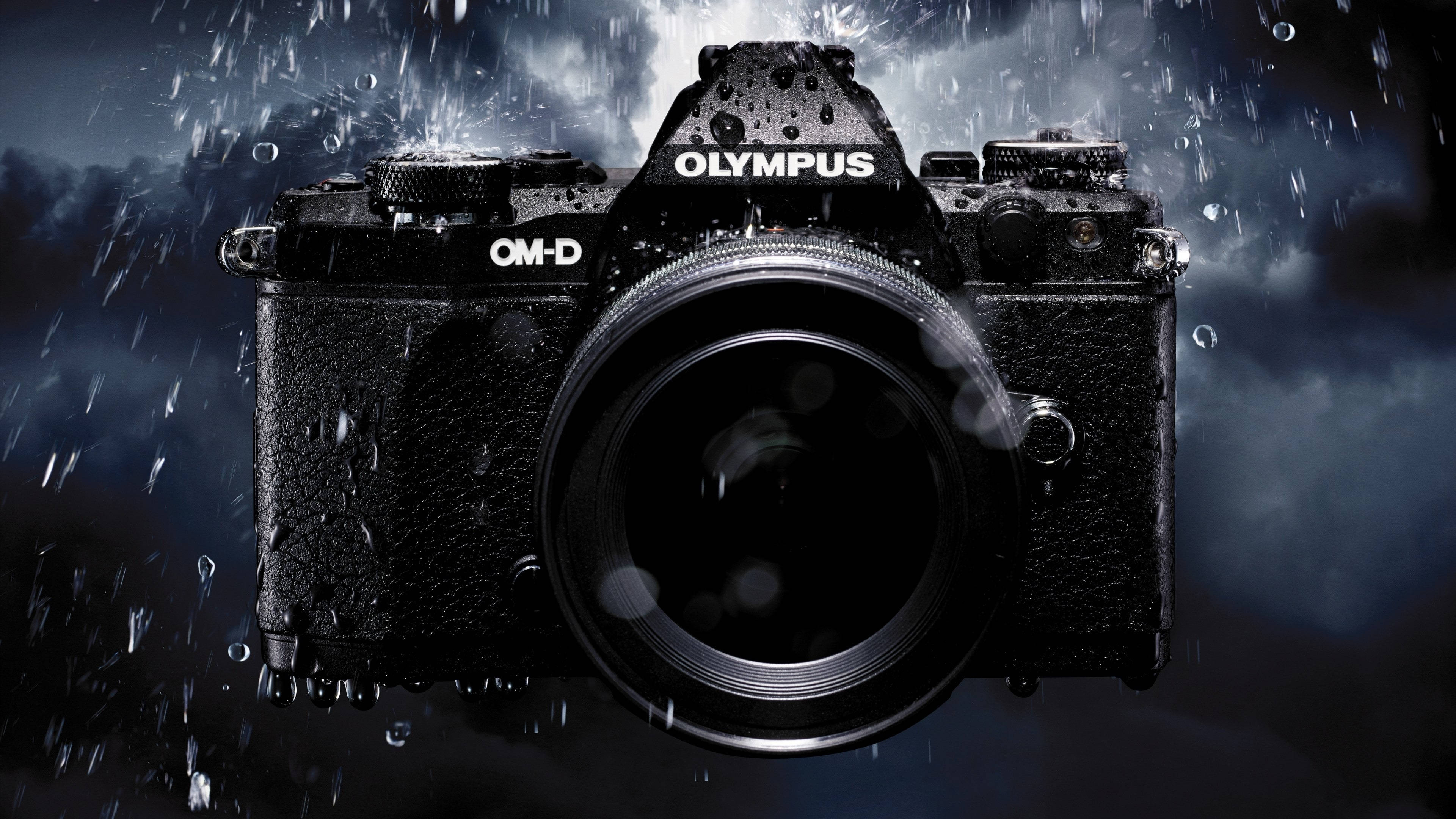相機 桌布 壁紙 — 一部黑色Olympus OM-D相機，佈滿雨滴，背景是暴風雨的黑暗天空和落下的雨。