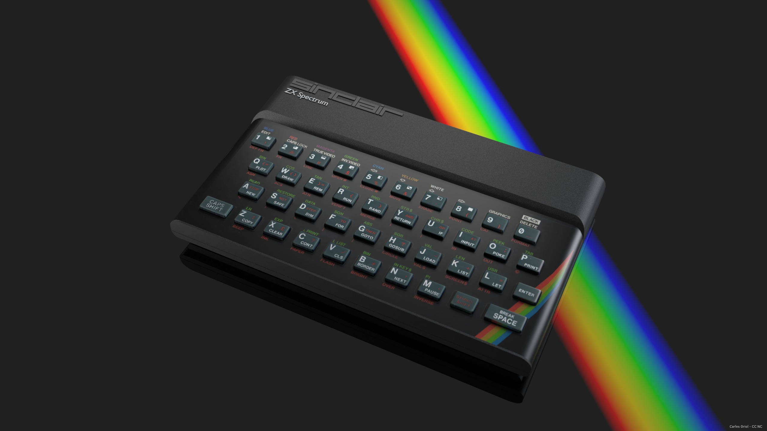 Spectrum 桌布 壁紙 — 一部黑色Sinclair ZX Spectrum電腦傾斜放置在深色背景上，一道鮮豔的彩虹稜鏡光束斜向穿過畫面。