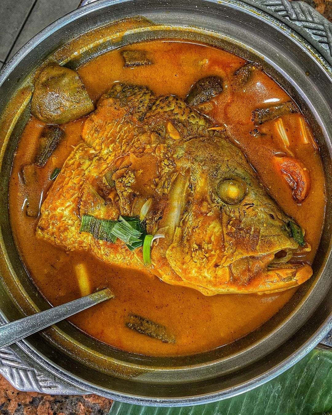 金屬碗中冒煙的魚咖哩，配有完整魚頭和綠色香草。 — 食物動圖 壁紙