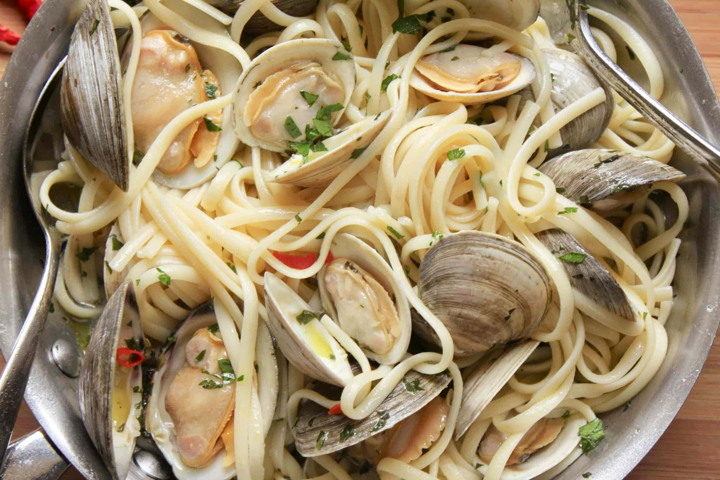 Clam 桌布 壁紙 — 一鍋冒煙的蜆肉義大利麵，飾以新鮮歐芹和紅辣椒片。