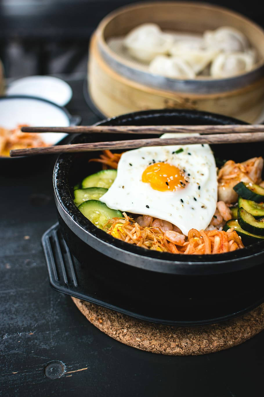 烹飪 桌布 壁紙 — 一鍋冒煙的韓國石鍋拌飯，上面放著太陽蛋和新鮮蔬菜，筷子已準備好。