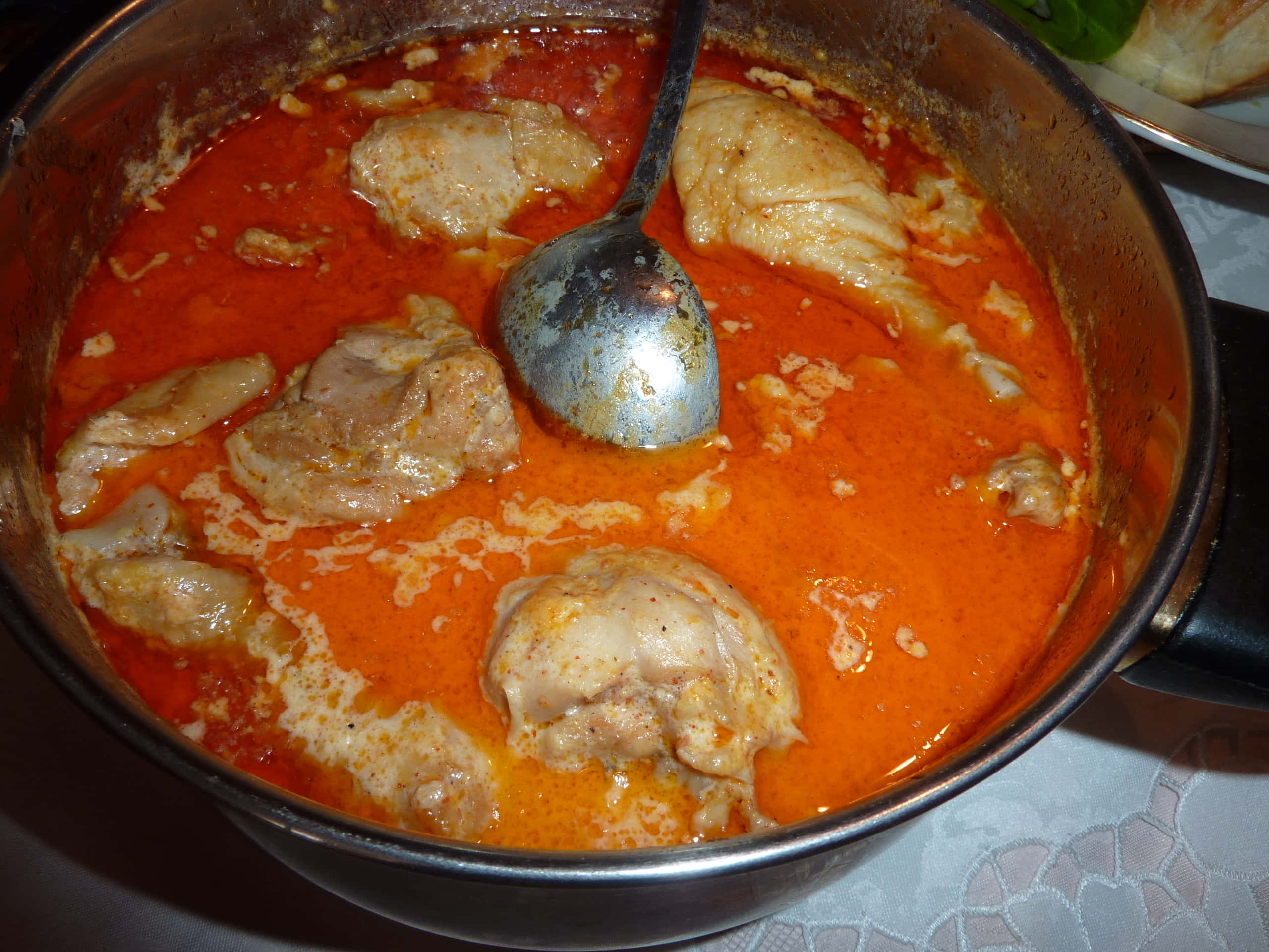 Chicken 桌布 壁紙 — 一鍋冒著熱氣的濃郁橙色咖哩，內有嫩滑雞肉塊，金屬湯匙擱在醬汁中。