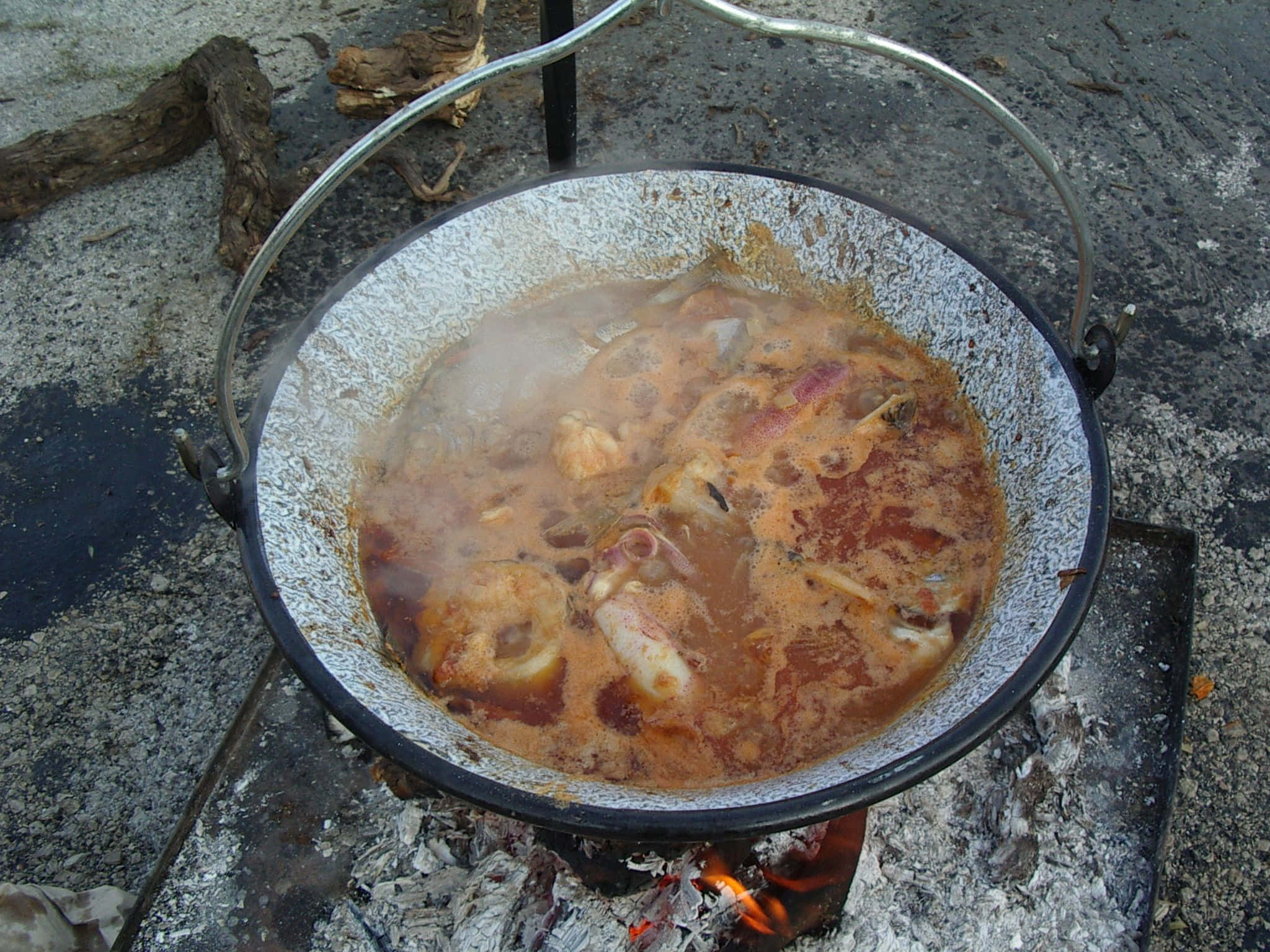 Croatia 桌布 壁紙 — 一鍋冒著熱氣的燉菜在岩石戶外火坑的餘燼上慢煮。