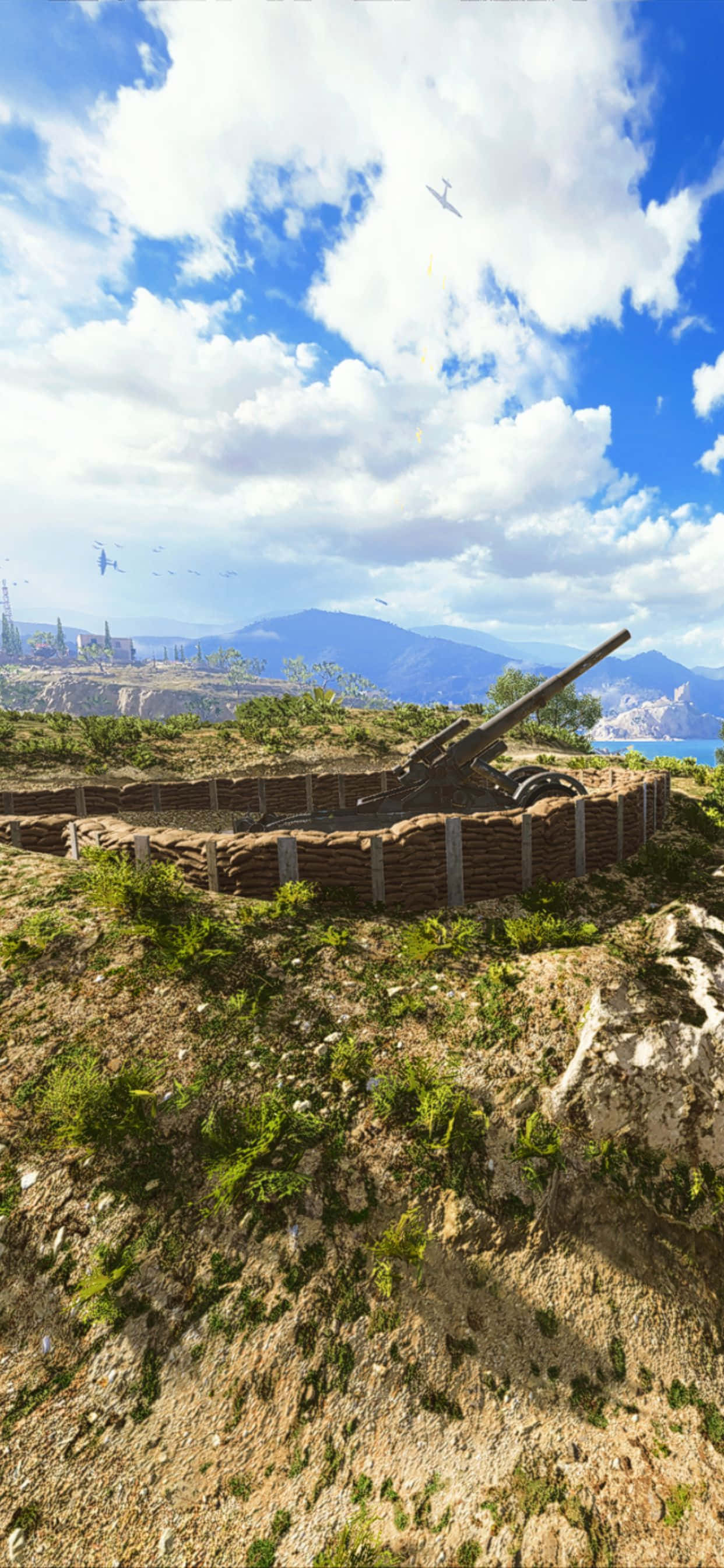 iPhone Xs Max Battlefield V 桌布 壁紙 — 一門風化的火炮安放在岩石山坡上，俯瞰著沿海城市，天空湛藍，白雲朵朵。