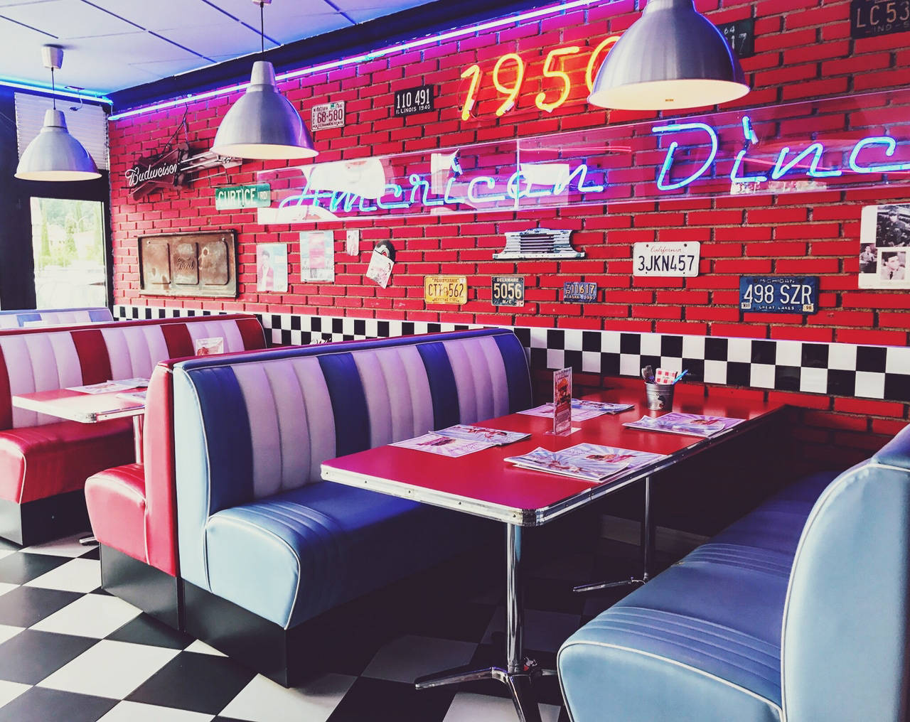 Diner 桌布 壁紙 — 一間1950年代復古美式餐廳，設有紅磚牆、霓虹燈招牌、棋盤地板和色彩繽紛的乙烯基卡座。