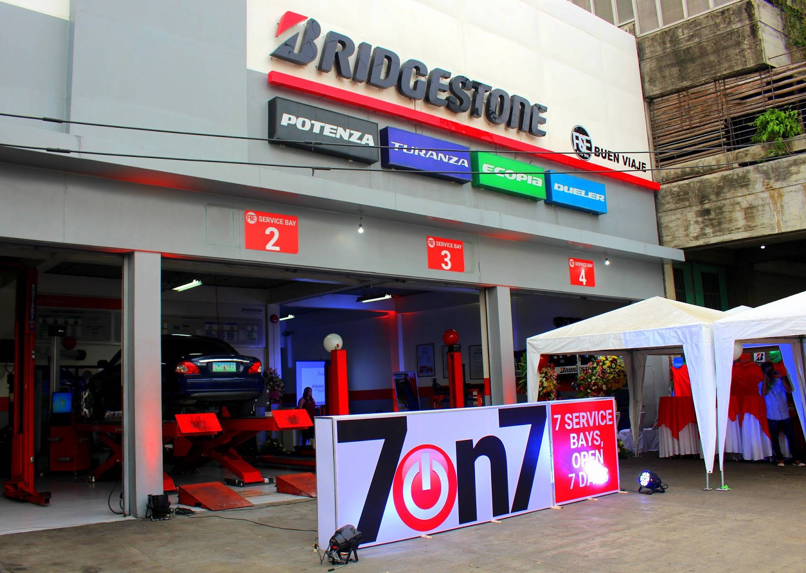 標誌 桌布 壁紙 — 一間Bridgestone輪胎店，設有開放式服務車位，前方有一個大型7on7標誌。