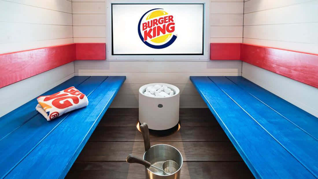 漢堡王 桌布 壁紙 — 一間Burger King品牌的桑拿房，配有藍色長凳、紅色飾邊和牆上發光的標誌。