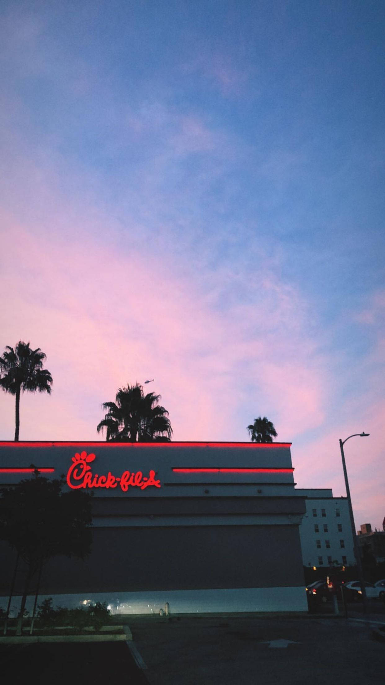 chick 桌布 壁紙 — 一間Chick-fil-A餐廳在帶有粉紅和藍色雲彩的暮色天空下，散發著紅色霓虹光芒。