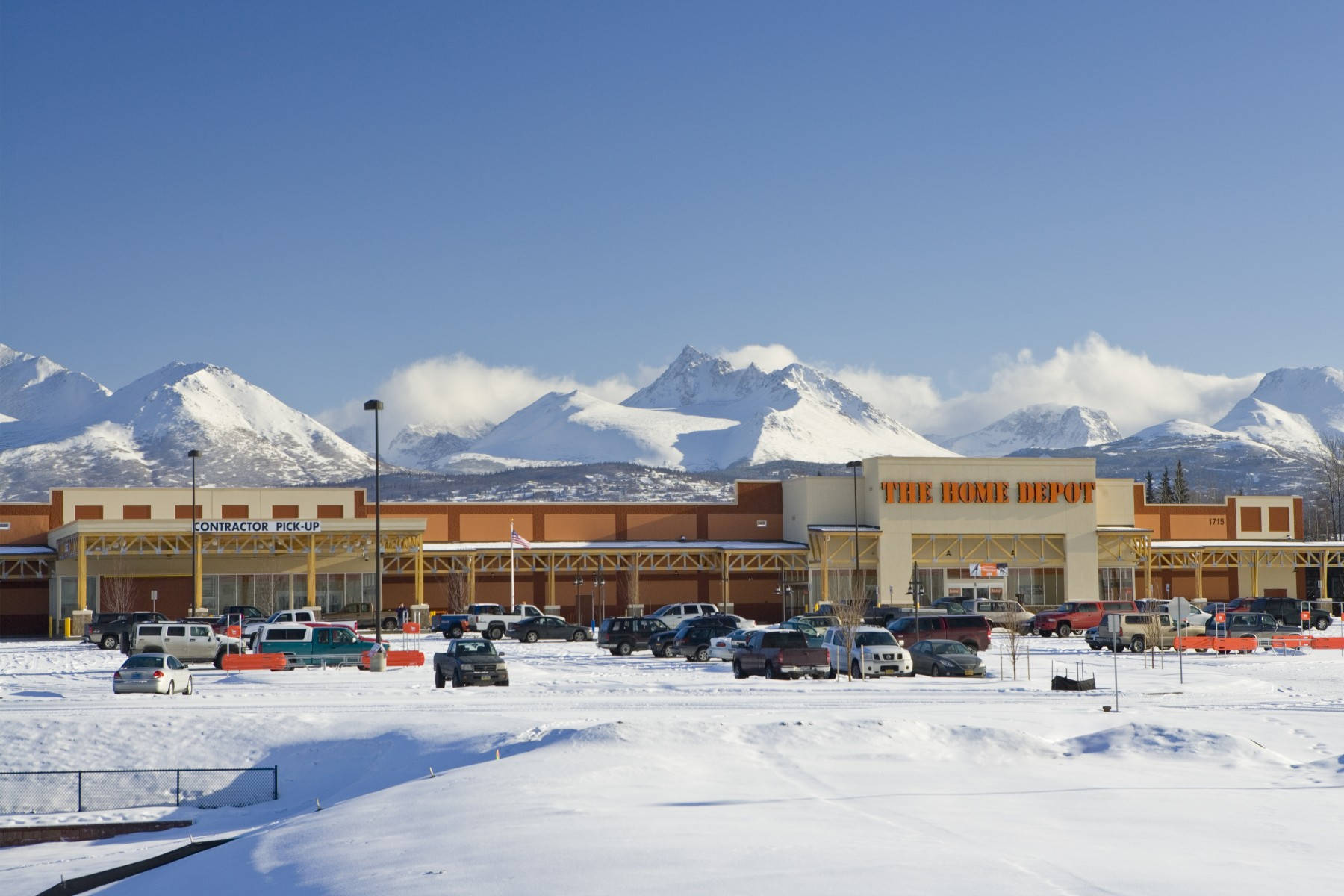 Home Depot 桌布 壁紙 — 一間Home Depot商店位於積雪的停車場，背後有白雪覆蓋的山脈在晴朗藍天下聳立。