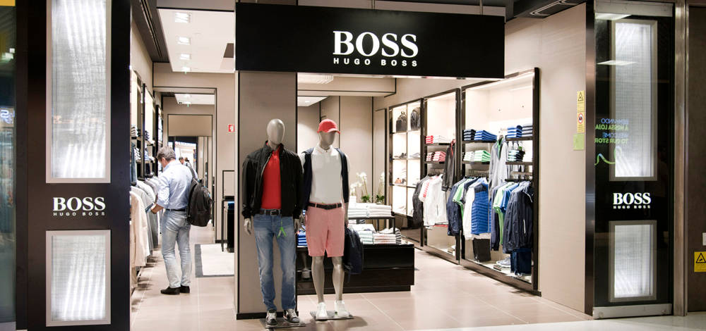高清 桌布 壁紙 — 一間Hugo Boss男裝店，內有穿著時尚服裝的人體模型和一位正在瀏覽貨架的購物者。