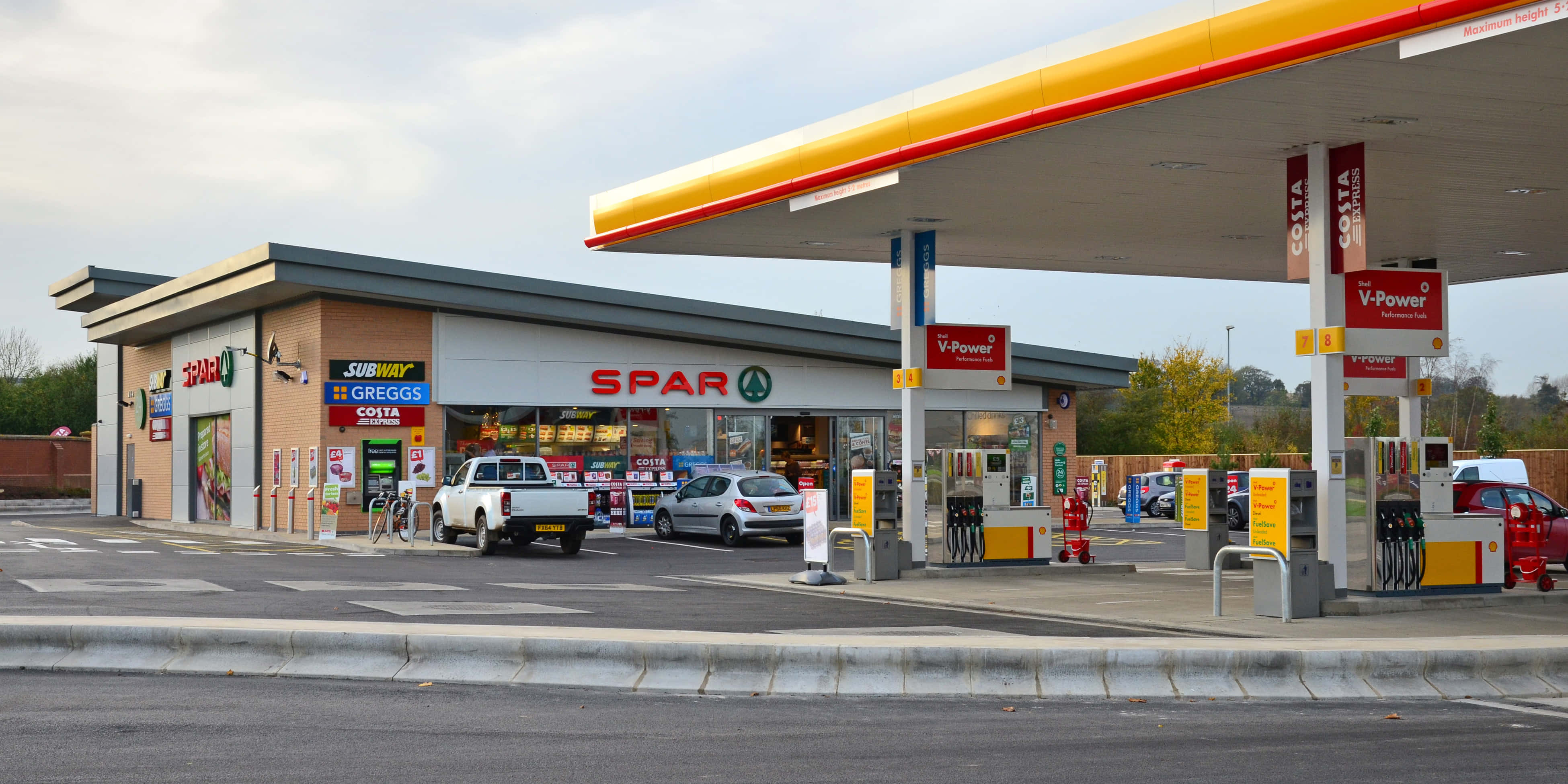 Petrol Station 桌布 壁紙 — 一間SPAR便利商店和V-Power加油站，汽車在油泵旁，天空多雲。