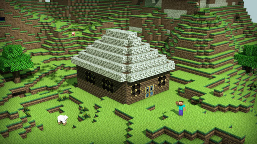房屋 桌布 壁紙 — 一間像素化的Minecraft房屋，帶有石頭金字塔屋頂，坐落在被樹木和一隻羊環繞的草坡上。