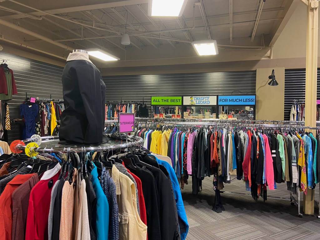 Clothes 桌布 壁紙 — 一間光線充足的二手商店，充滿色彩繽紛的衣架和一個穿著黑色外套的人體模型。