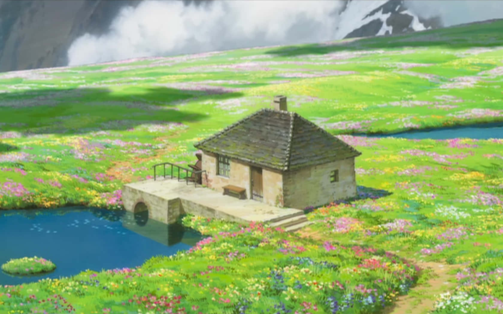 背景有山脈的彩色野花田中的池塘旁的石頭小屋。 — 吉卜力工作室 GIF 壁紙