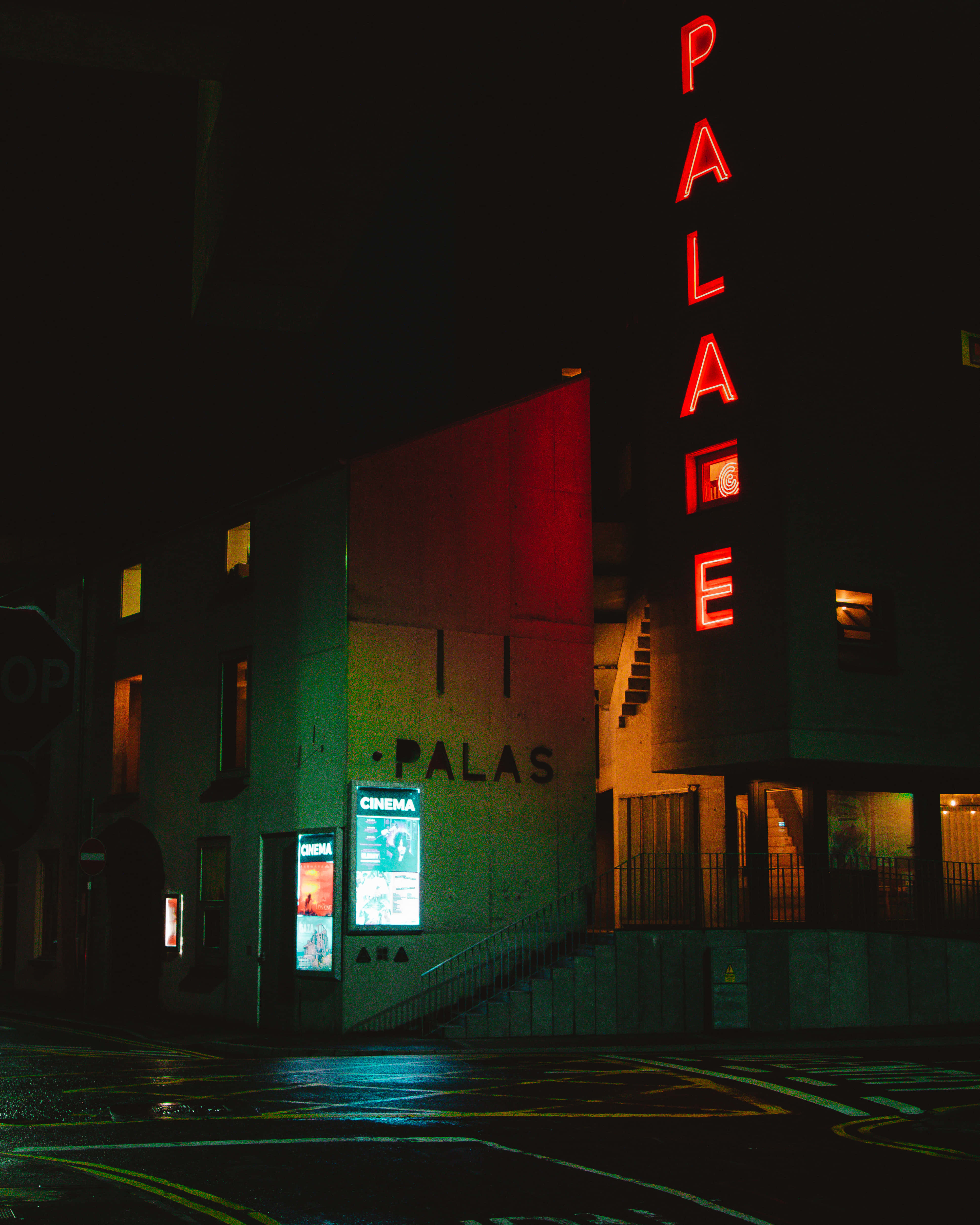 Sad Vibes 桌布 壁紙 — 一間名為「PALACE」的霓虹燈電影院，在漆黑的都市夜晚中發出紅光，濕漉漉的人行道反射出五彩繽紛的燈光。