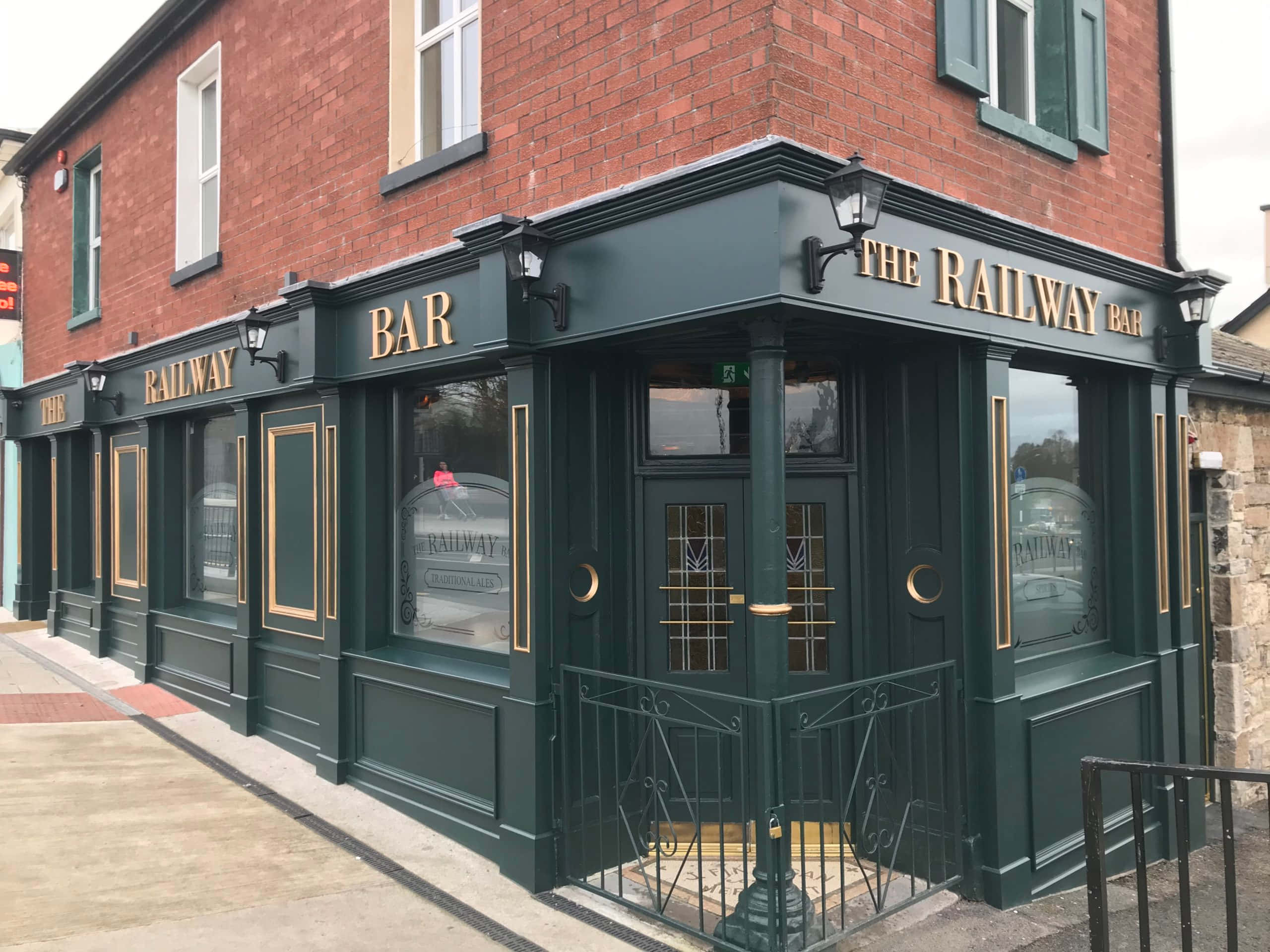 Bar 桌布 壁紙 — 一間名為「The Railway Bar」的經典磚造酒吧，帶有深綠色飾邊和金色字樣，矗立在陰天街道的角落。