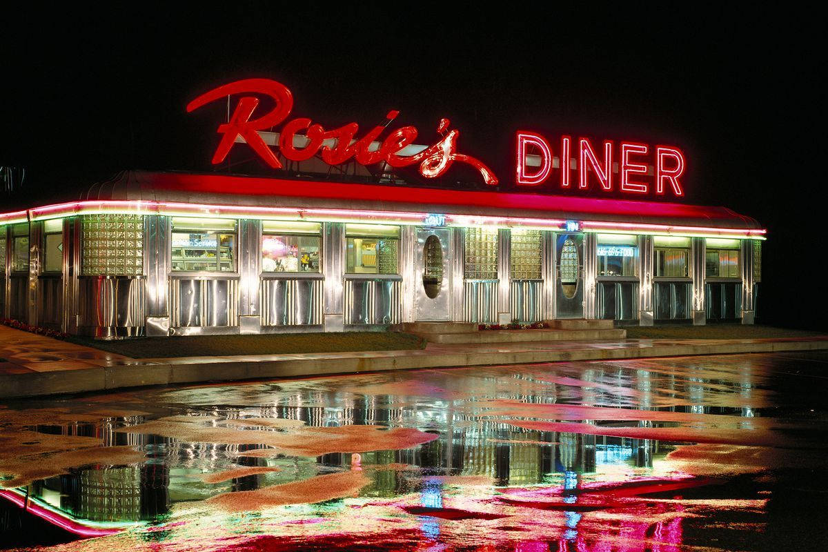 Diner 桌布 壁紙 — 一間名為Rosie's的復古餐廳，在漆黑的夜空下閃爍著鮮豔的紅色霓虹燈招牌，燈光生動地倒映在下方濕漉漉的路面上。