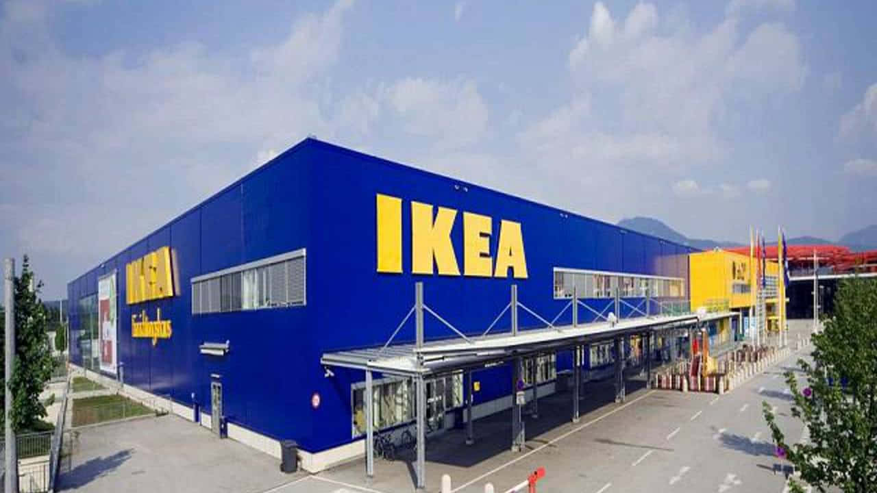 Ikea 桌布 壁紙 — 一間大型藍色IKEA商店，在部分多雲的天空和遠山背景下，帶有醒目的黃色標牌。