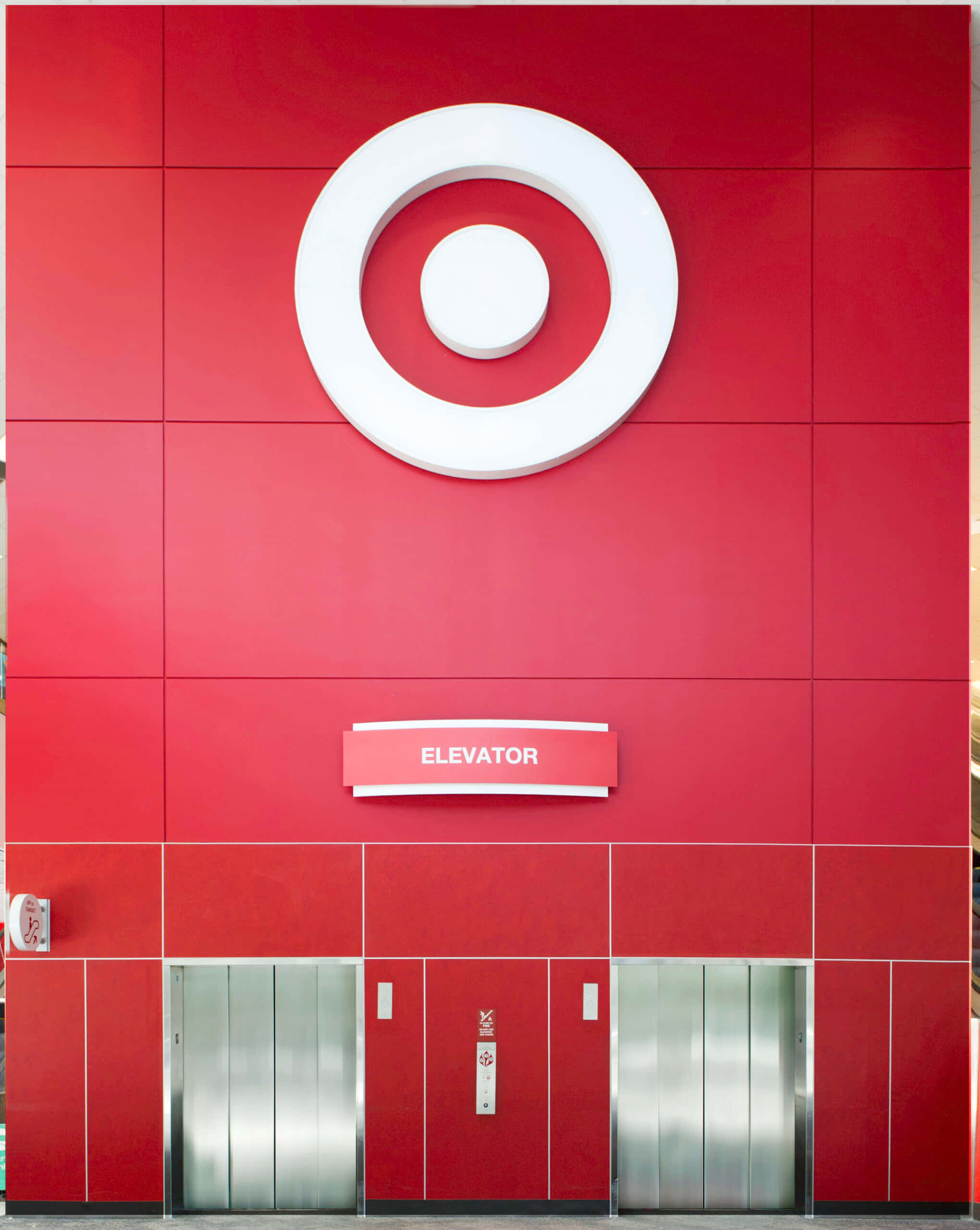 elevator 桌布 壁紙 — 一間大膽的紅色Target商店外牆，在時尚的電梯入口上方有一個大型白色靶心標誌。
