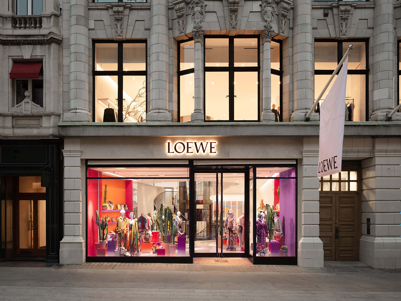 Store 桌布 壁紙 — 一間宏偉的Loewe精品店，擁有華麗的石頭建築和充滿活力的粉紫色室內燈光，照亮了人體模型和仙人掌展示。