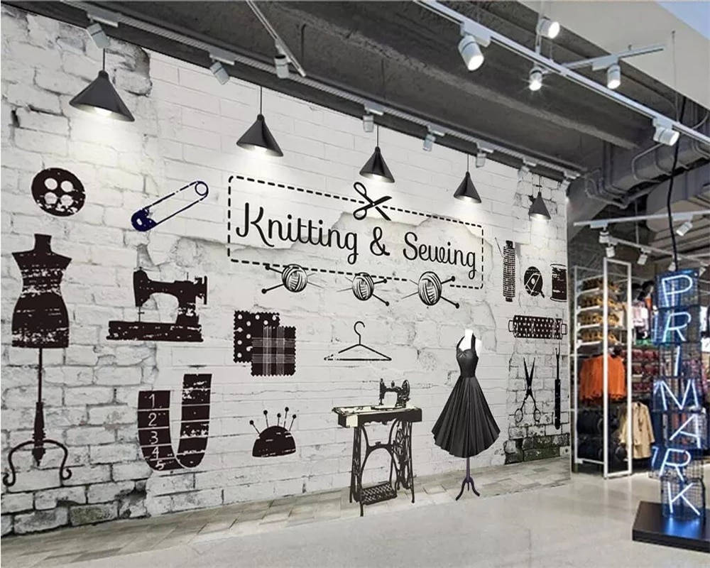 Clothes 桌布 壁紙 — 一間復古裁縫店，在工業燈光下，白色磚牆上展示著黑色剪影的人體模型、縫紉機和布料圖案。