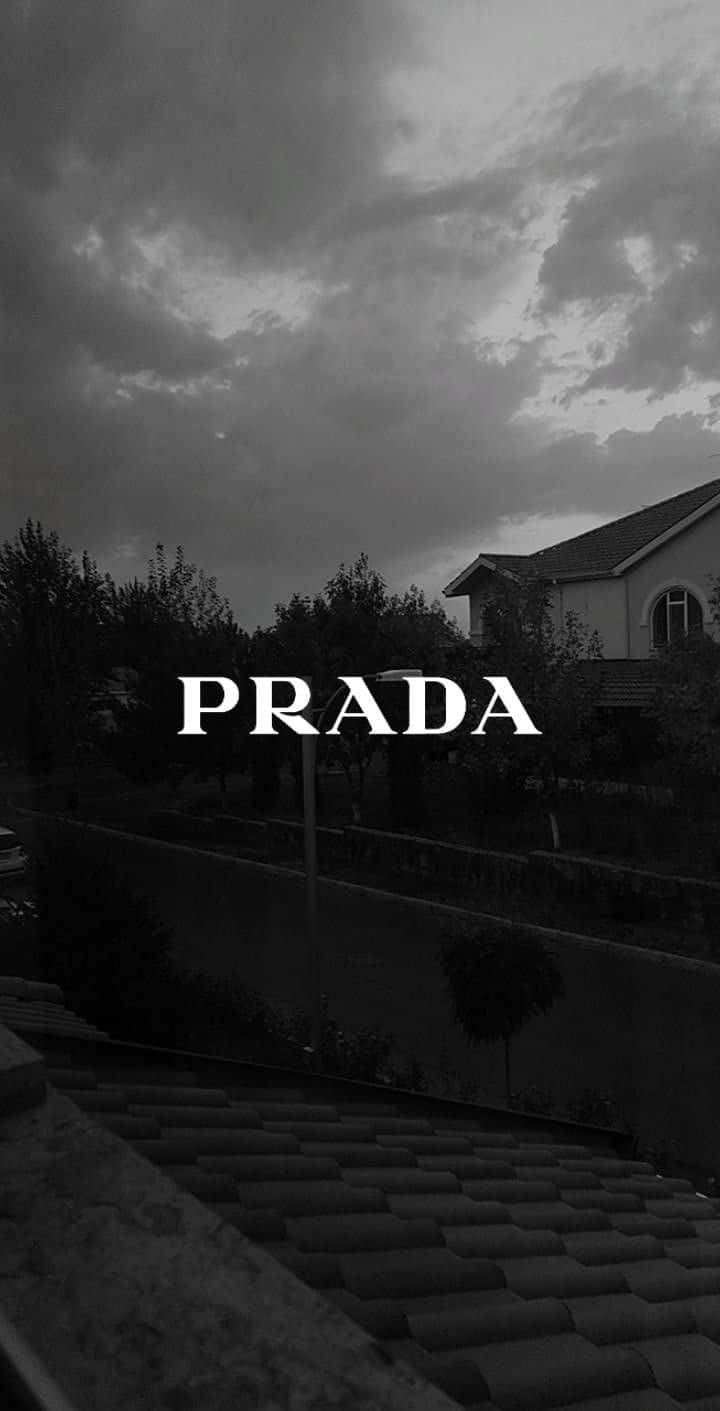 Prada 桌布 壁紙 — 一間房屋在戲劇性多雲天空下的單色屋頂景觀，上面覆蓋著PRADA字樣。