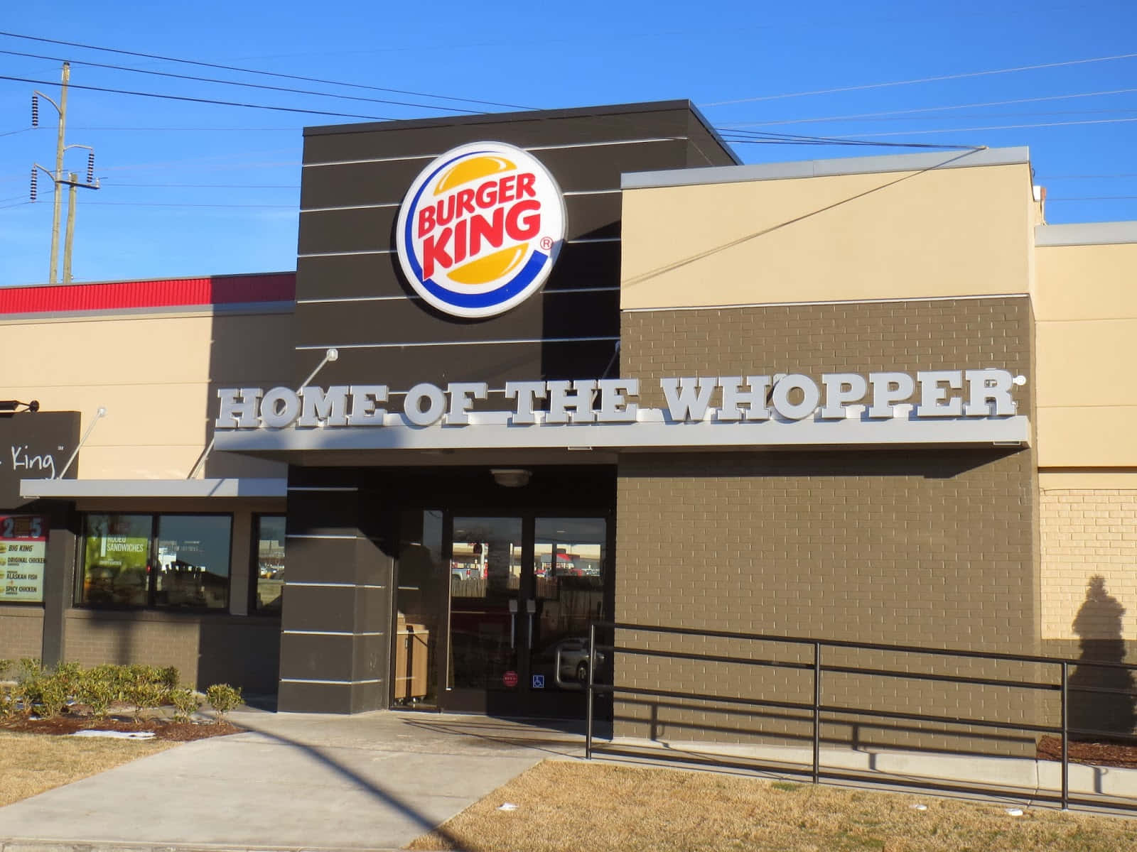 漢堡王 桌布 壁紙 — 一間明亮的Burger King餐廳，在清澈藍天下有「HOME OF THE WHOPPER」標誌。