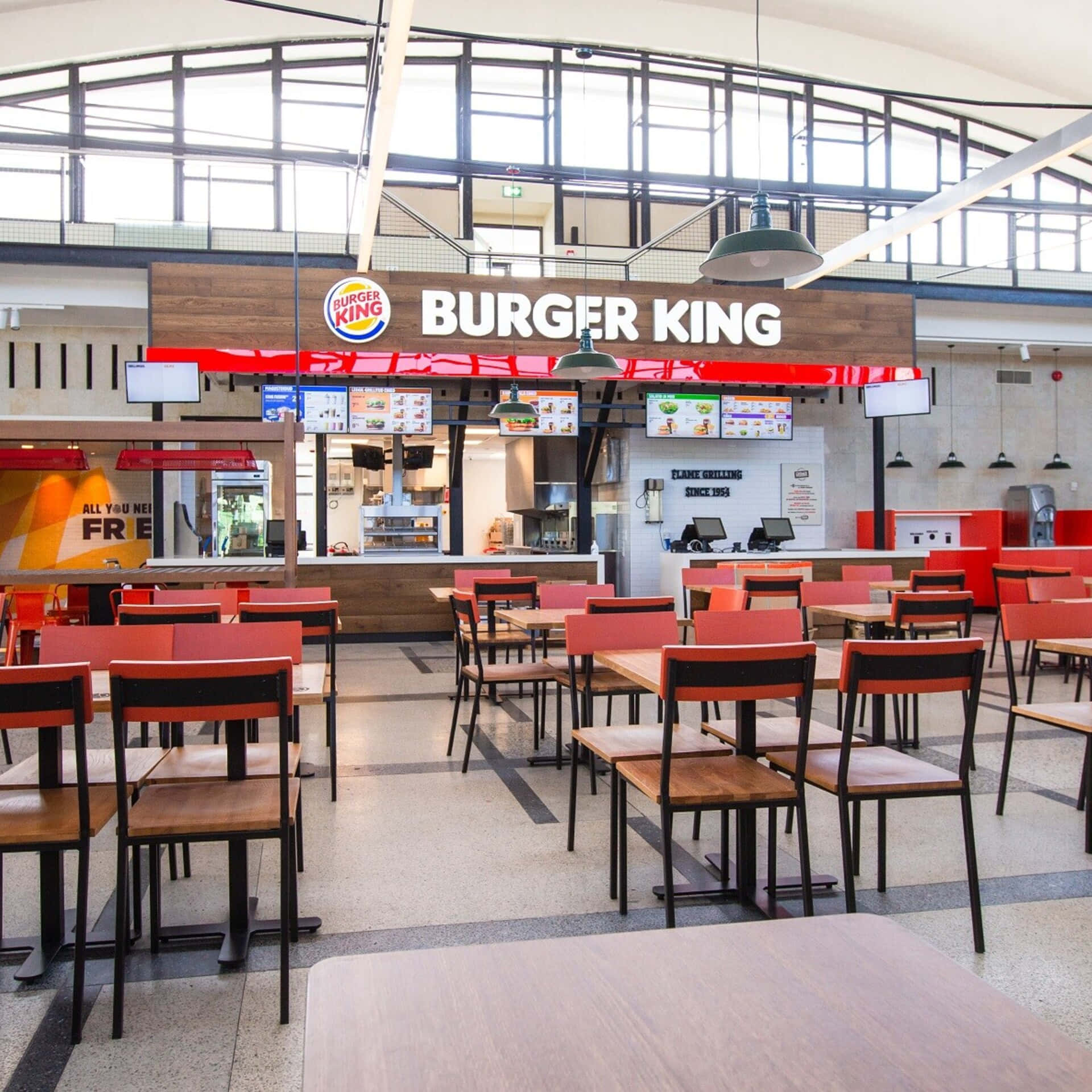 Burger King 桌布 壁紙 — 一間明亮的Burger King餐廳，設有紅色椅子、木桌和大窗戶，讓自然光線透入。