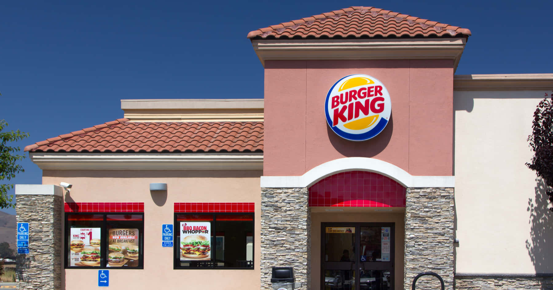 Burger King 桌布 壁紙 — 一間明亮的Burger King餐廳，擁有紅色瓦片屋頂和顯眼的標誌，在清澈的藍天下。