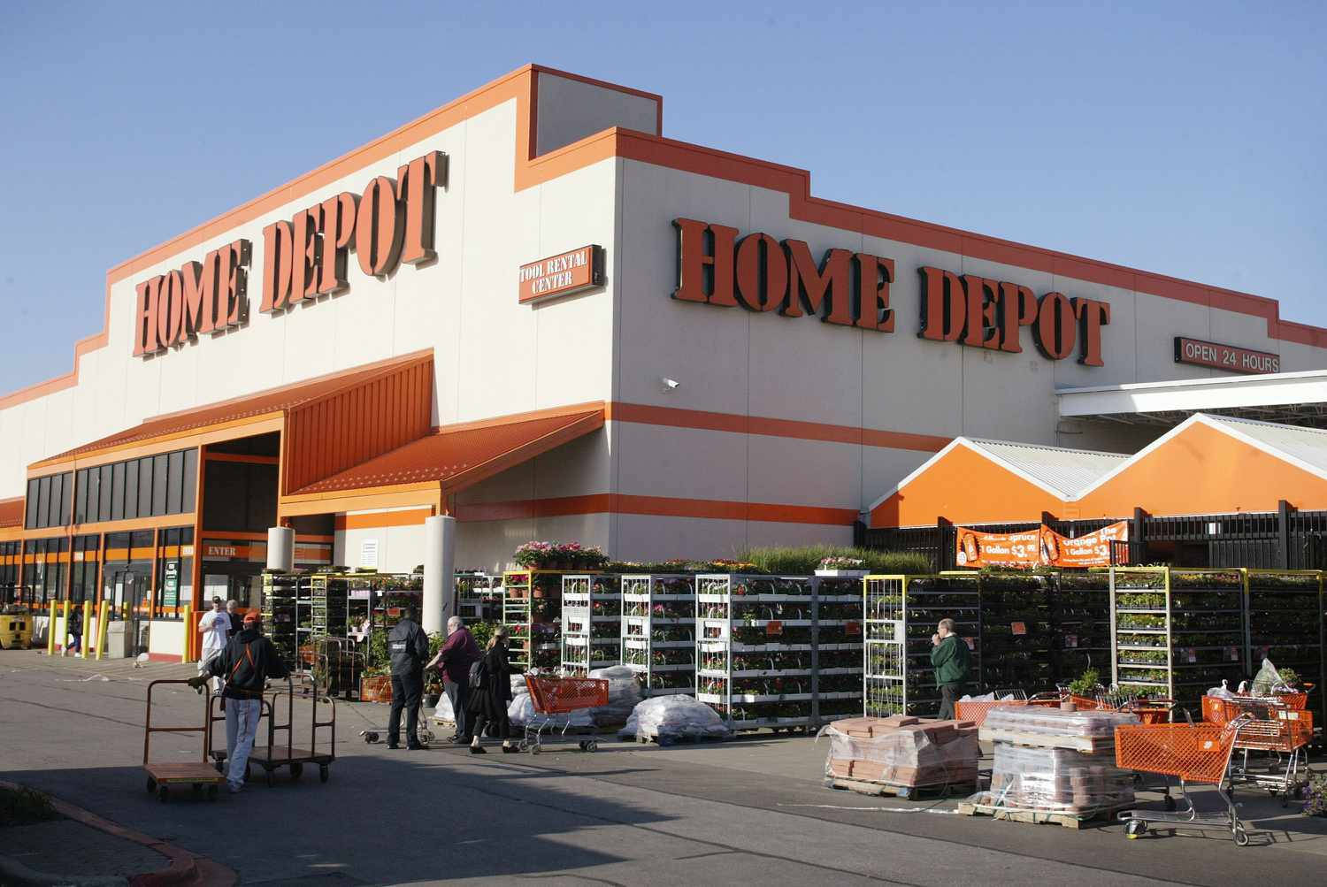 Home Depot 桌布 壁紙 — 一間明亮的橙色和白色Home Depot商店，外面有顧客和購物車，在清澈的藍天下。