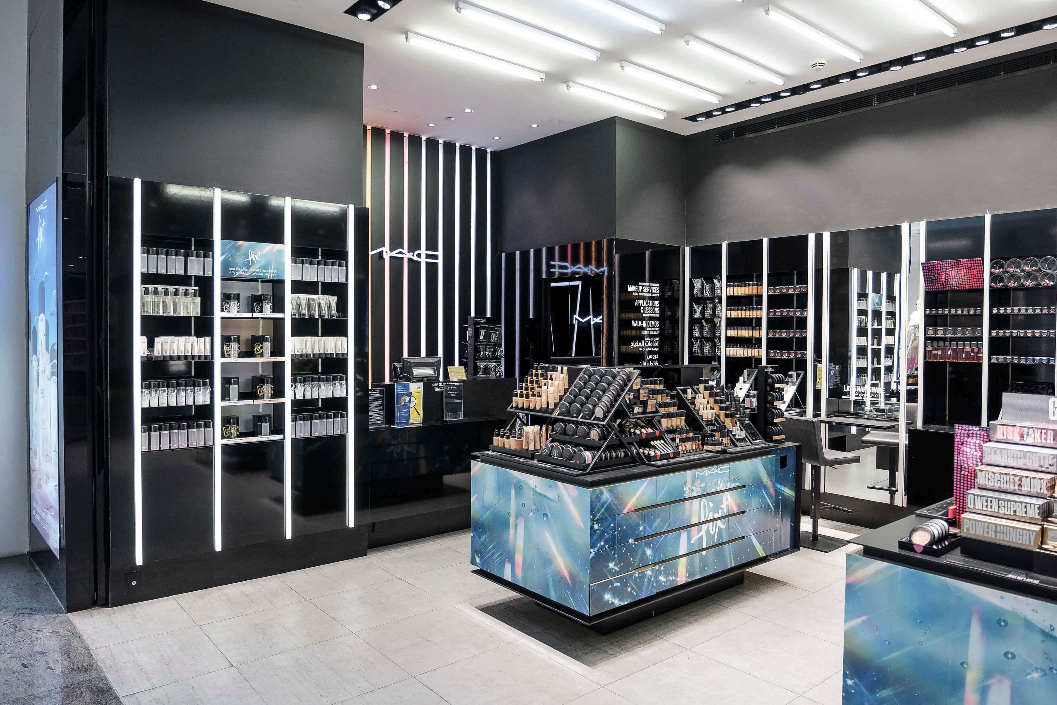 Mac Cosmetics 桌布 壁紙 — 一間時尚現代的MAC化妝品店，設有黑色貨架，發出白色LED燈光，以及一個宇宙主題的中央展示。