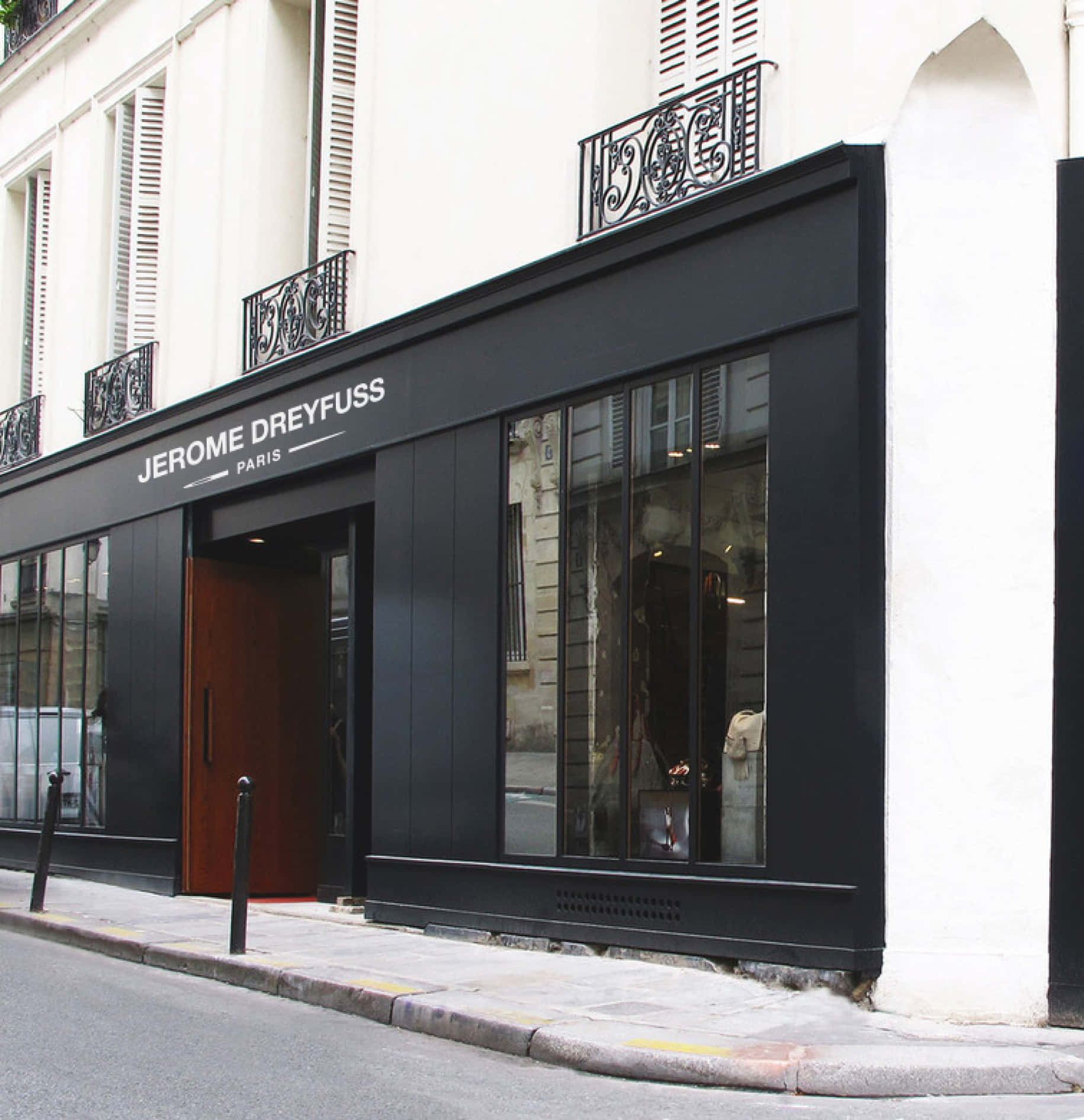 Building 桌布 壁紙 — 一間時尚的黑色精品店，帶有「JEROME DREYFUSS PARIS」標牌，矗立在巴黎街角，玻璃窗反射出城市環境。