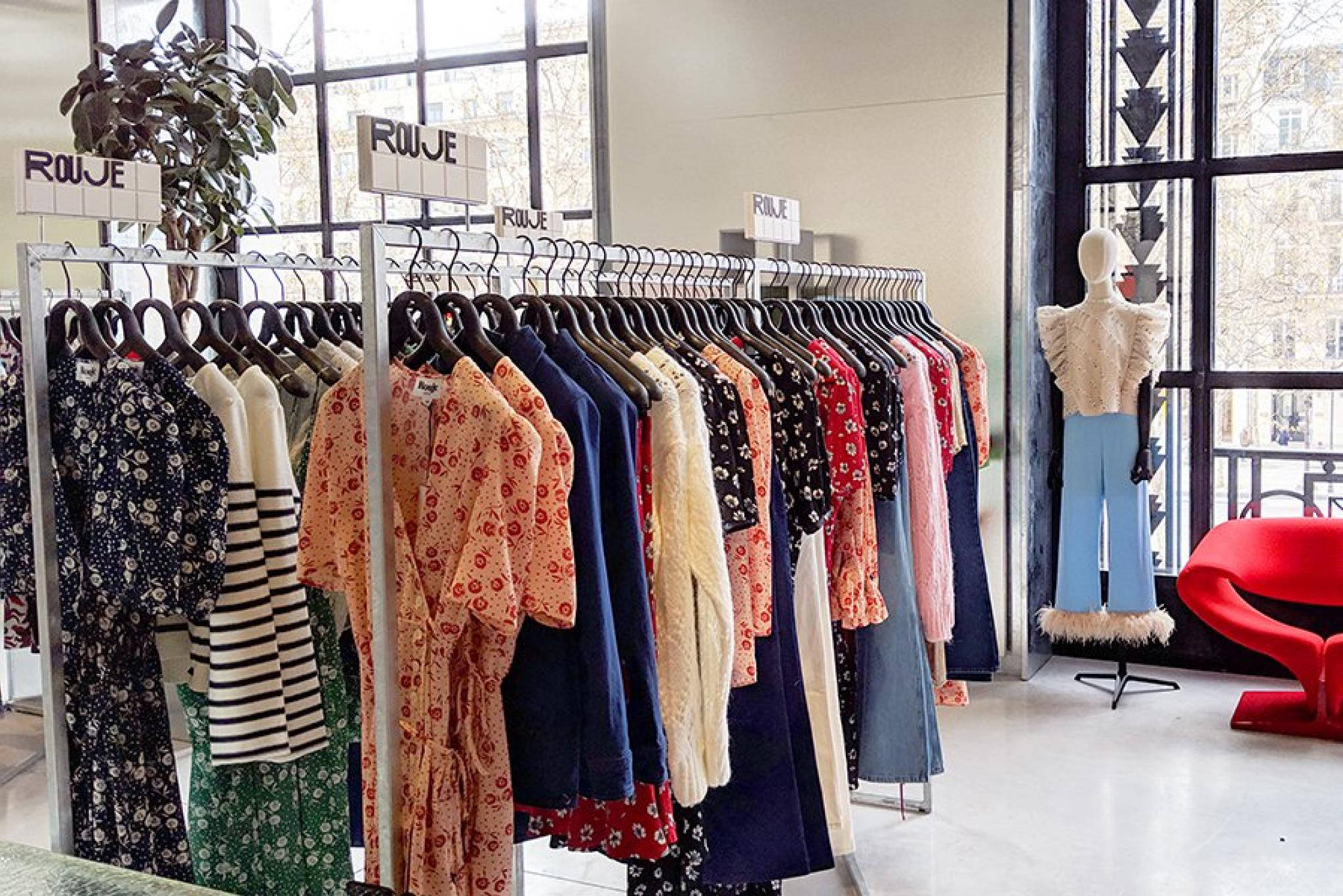 筆電 桌布 壁紙 — 一間時尚精品店在大型窗戶附近展示色彩繽紛的連衣裙，配有模特兒和紅色椅子。