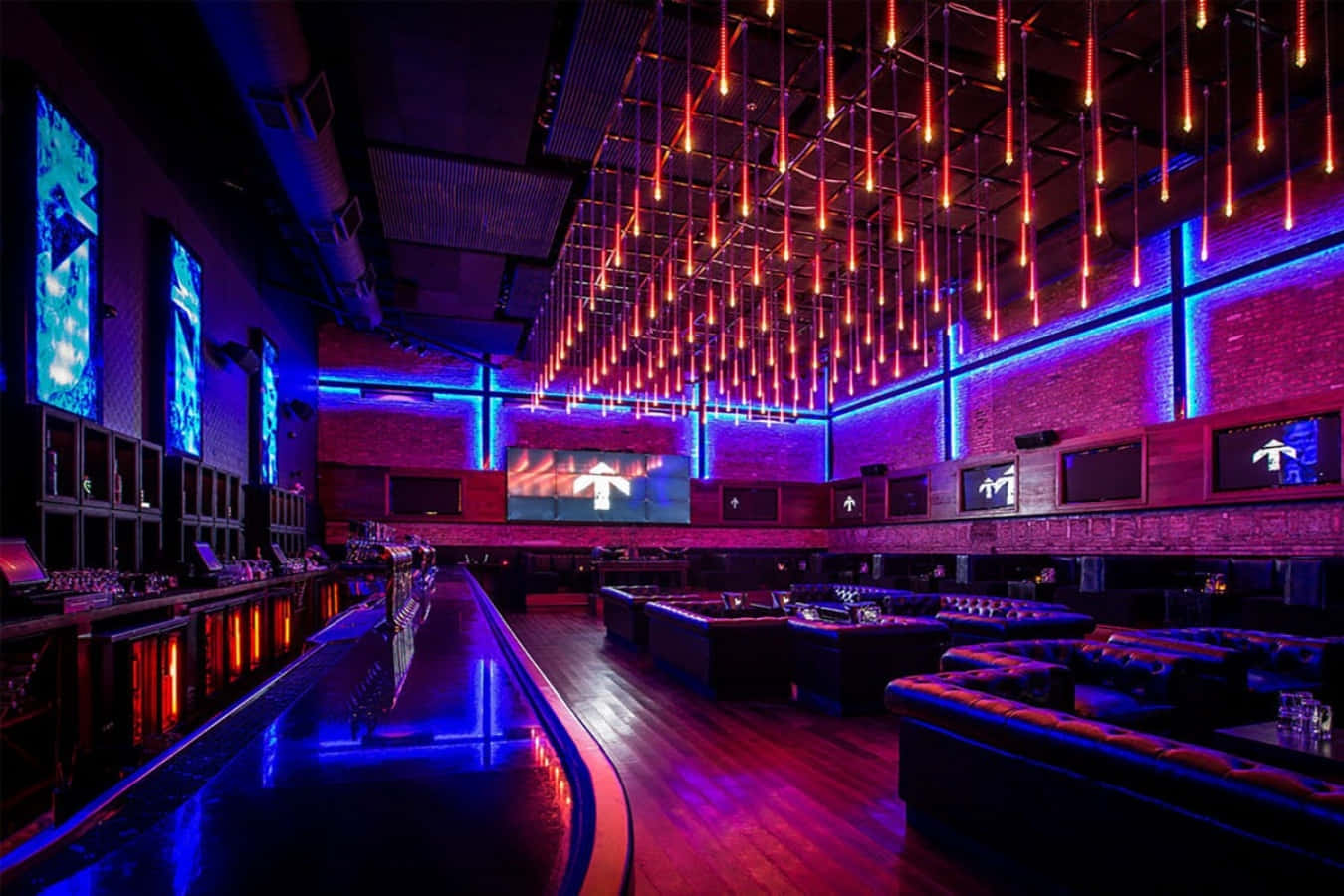 club 桌布 壁紙 — 一間未來風格的夜總會，以發光的紅色吊燈和藍色霓虹燈點綴，照亮了長長的吧檯和豪華的座位區。