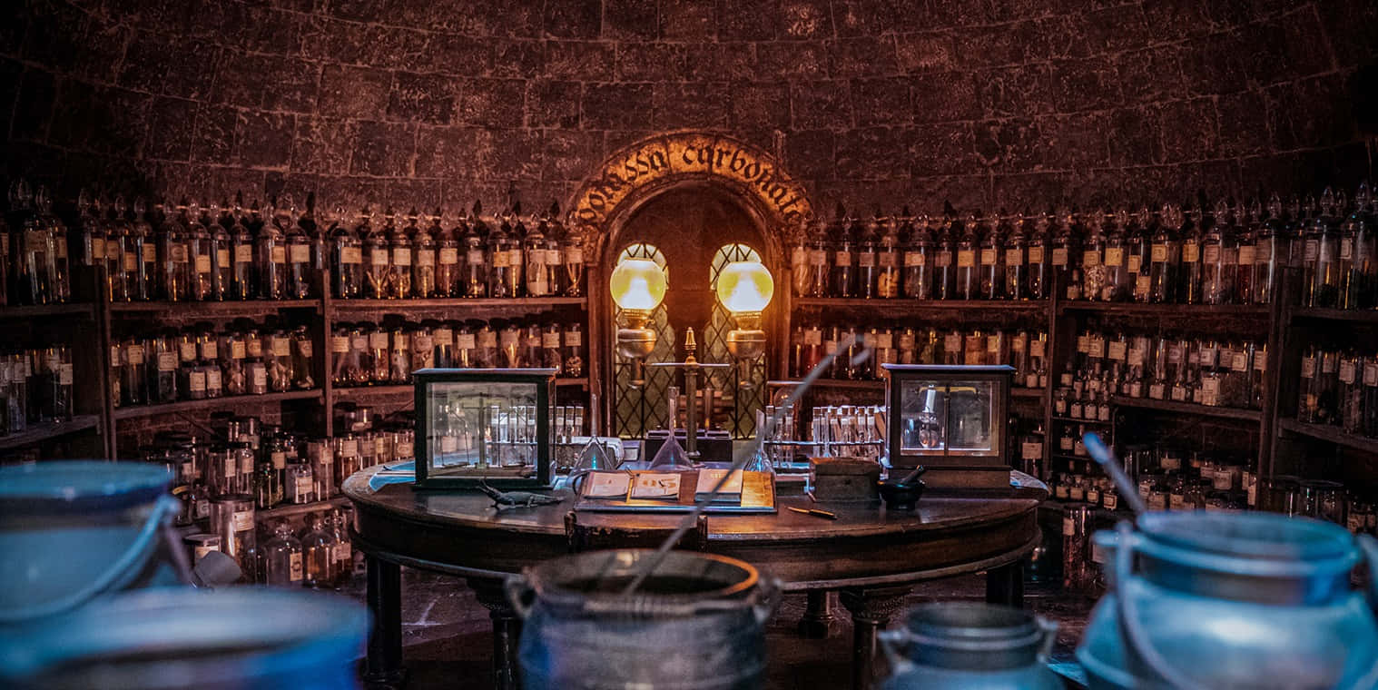 The Hogwarts Potions Class 桌布 壁紙 — 一間燈光昏暗的石製藥房，架子上擺滿藥水瓶，中央工作檯在發光的燈下。