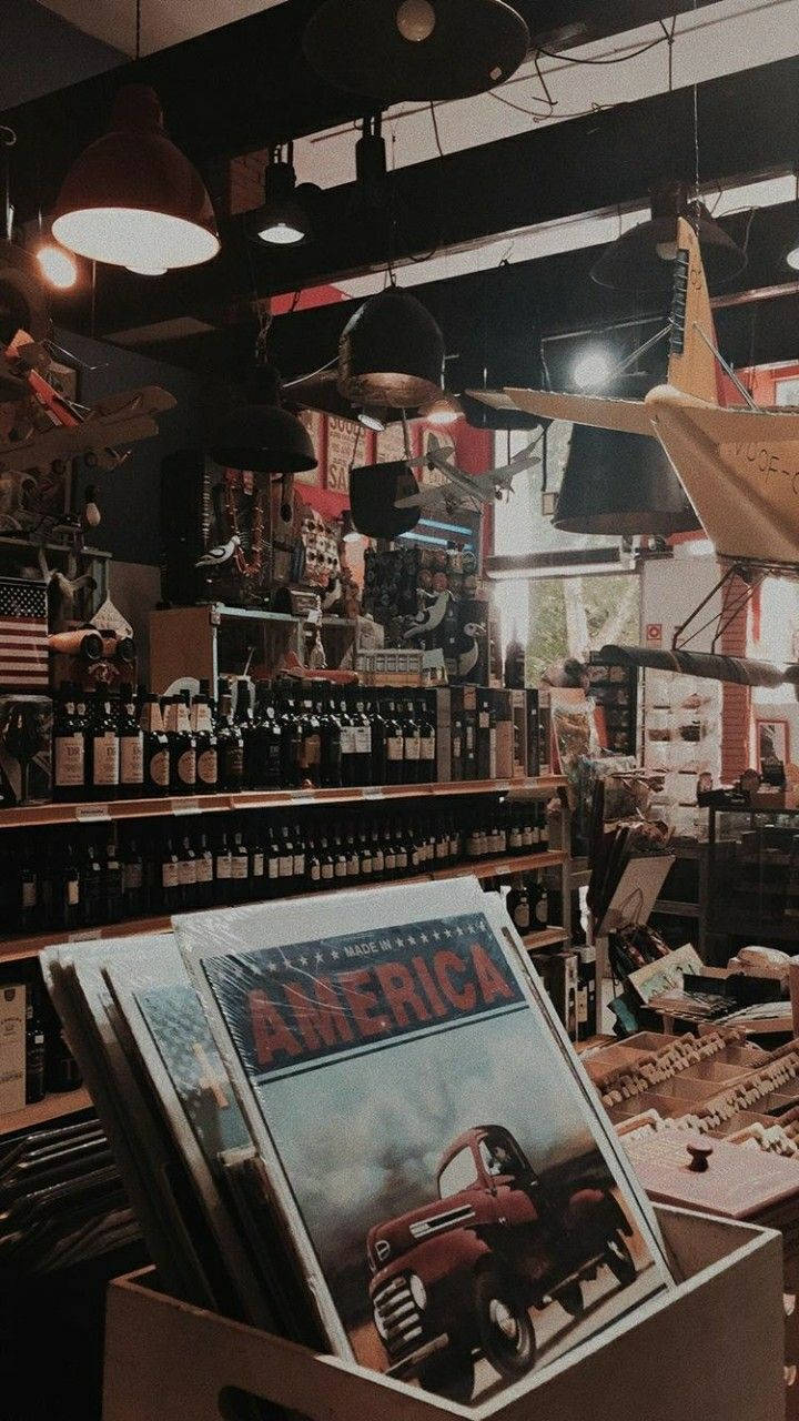 80s Retro 桌布 壁紙 — 一間燈光溫暖的復古商店，掛滿吊燈、酒瓶，還有一盒印有經典紅色卡車的「美國製造」唱片。