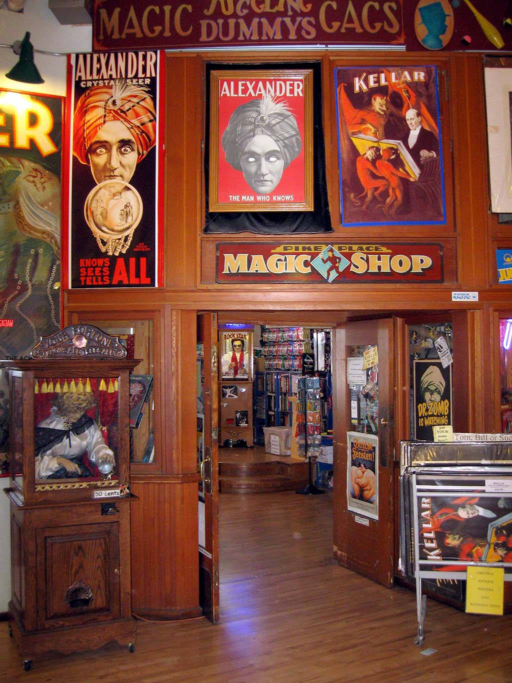 Pike Place Market 桌布 壁紙 — 一間燈光溫暖的復古魔術店，木製內部裝潢，牆上掛滿了經典魔術師海報，如亞歷山大和凱勒。